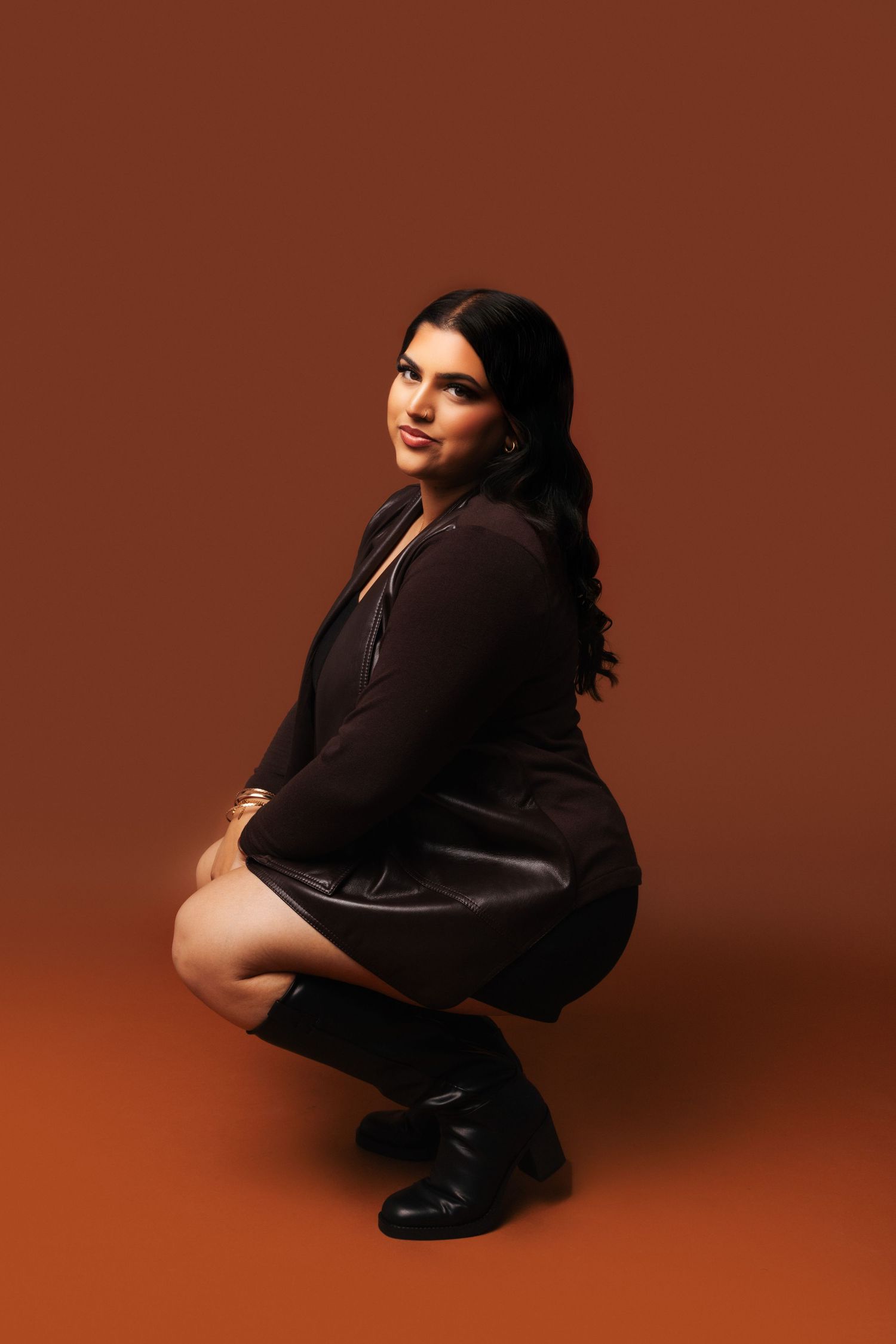 A figure in a black outfit poses against a brown backdrop in a series of artistic fashion portraits.