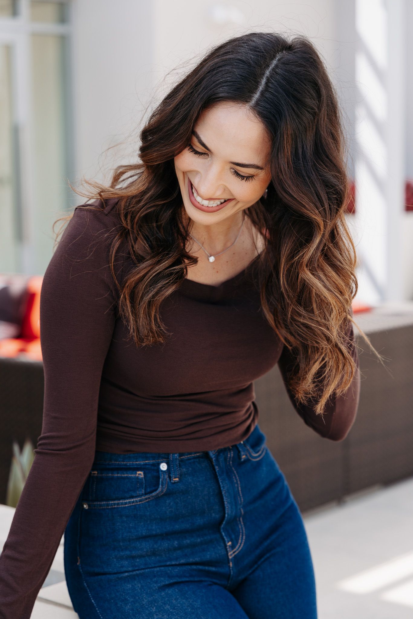Casual outfit styling with brown top and blue jeans shown in various poses near bright windows.