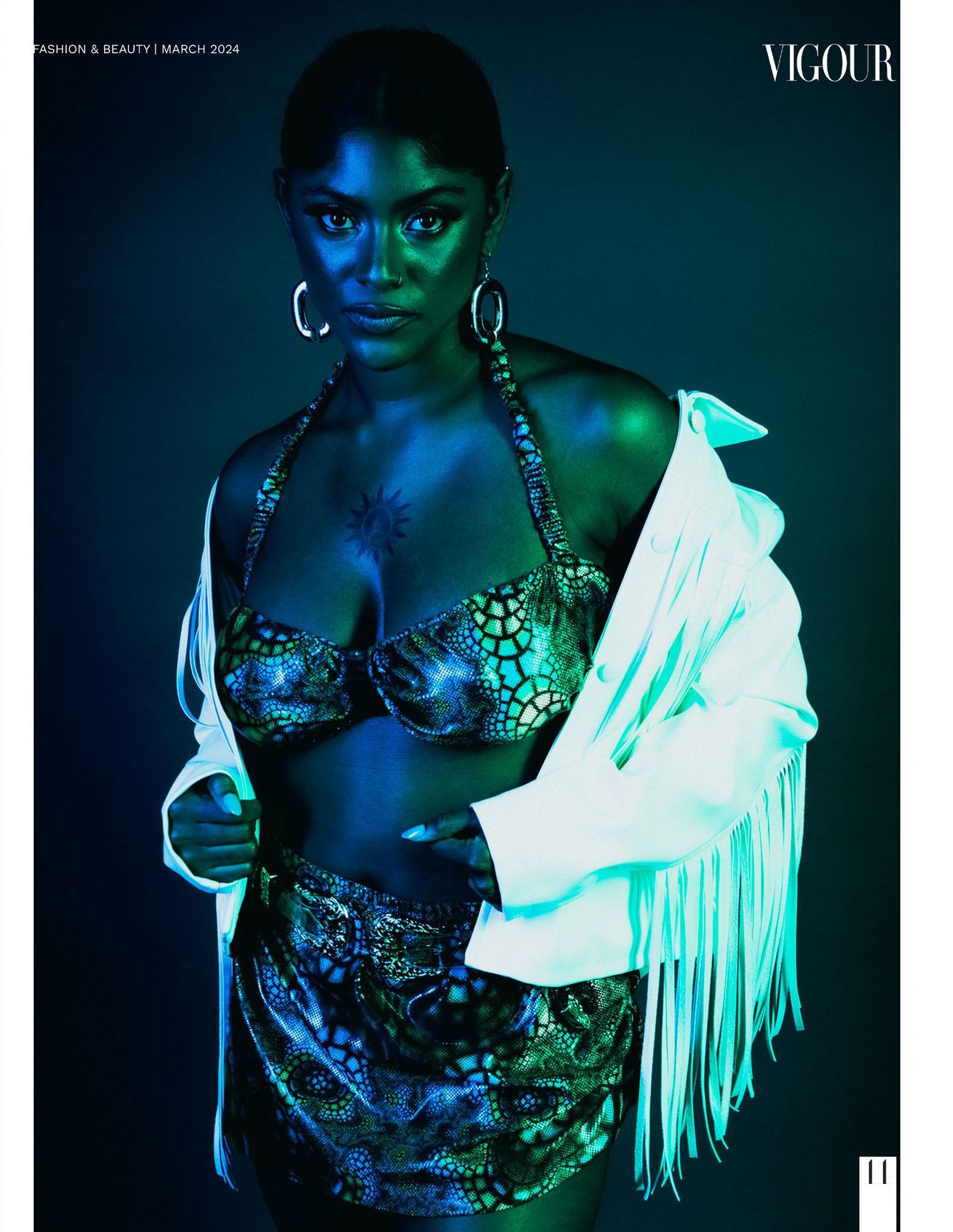 Fashion editorial with blue lighting showing sequined outfit and white fringed jacket against dark background.