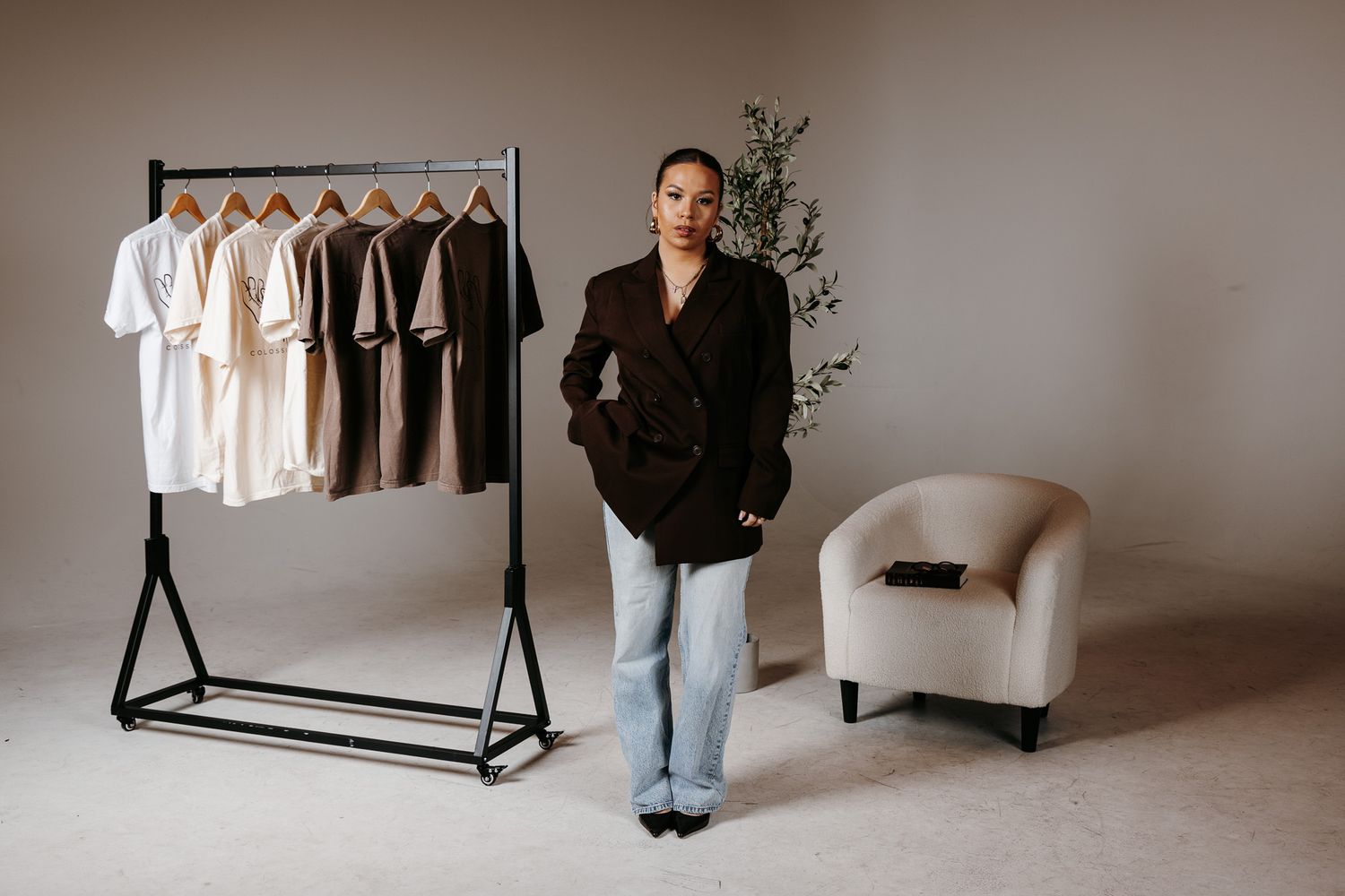 A modern clothing rack stands against a neutral wall displaying black and white garments in a minimalist setting.