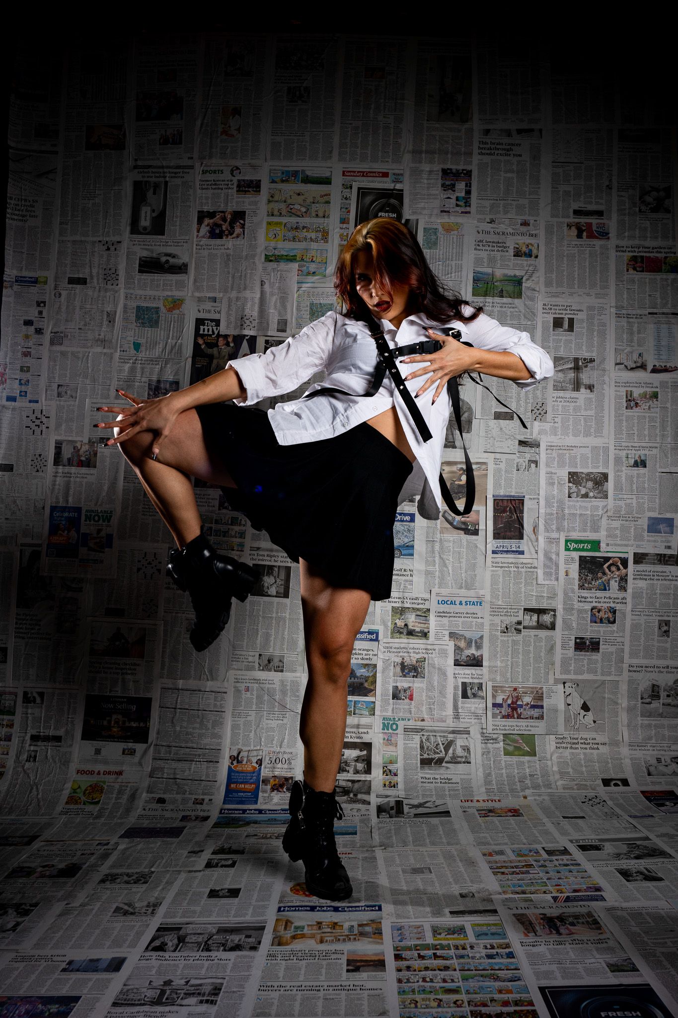 Dynamic dance sequence against newspaper wall backdrop showing expressive movement and high kicks in dramatic lighting.