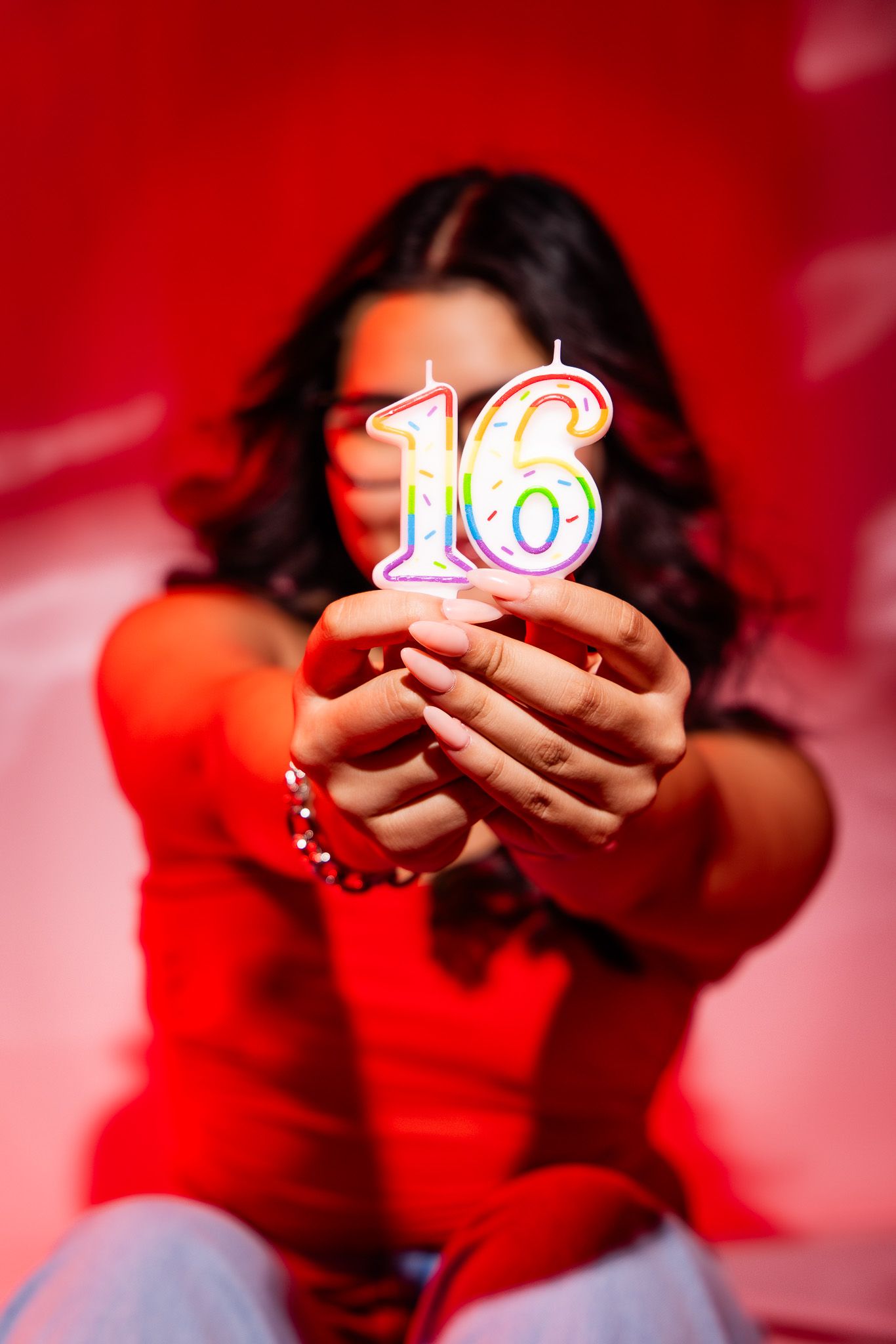 A series of red-tinted photos showing someone holding glowing number candles against a red background.