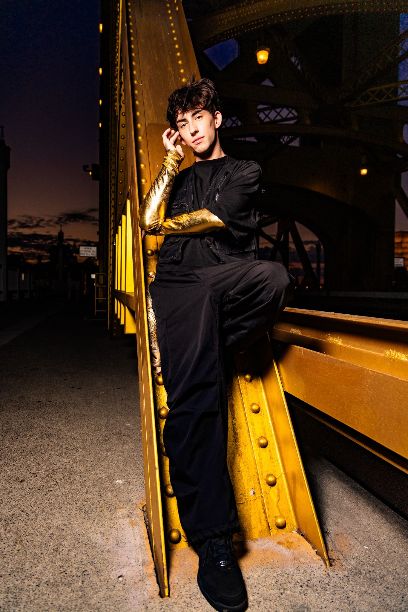 A dark silhouette stands against a yellow-lit wall at night in a dramatic urban setting.