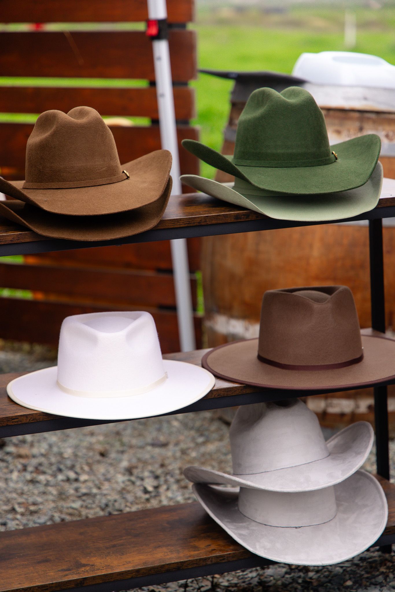 A collection of western-style cowboy hats in brown, white, and green colors displayed on wooden shelves.