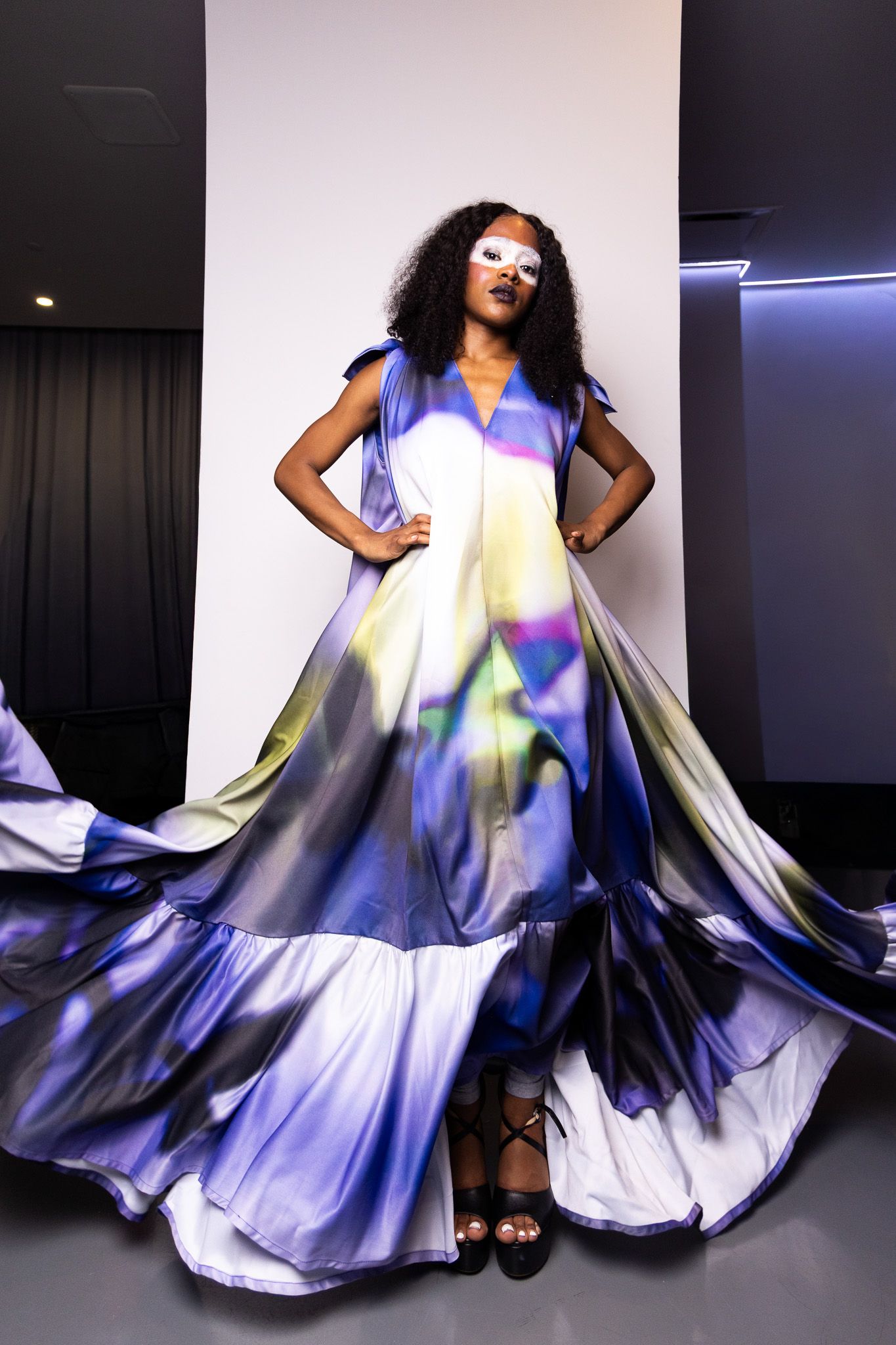 Flowing watercolor-style dress swirls during dynamic studio fashion photoshoot.