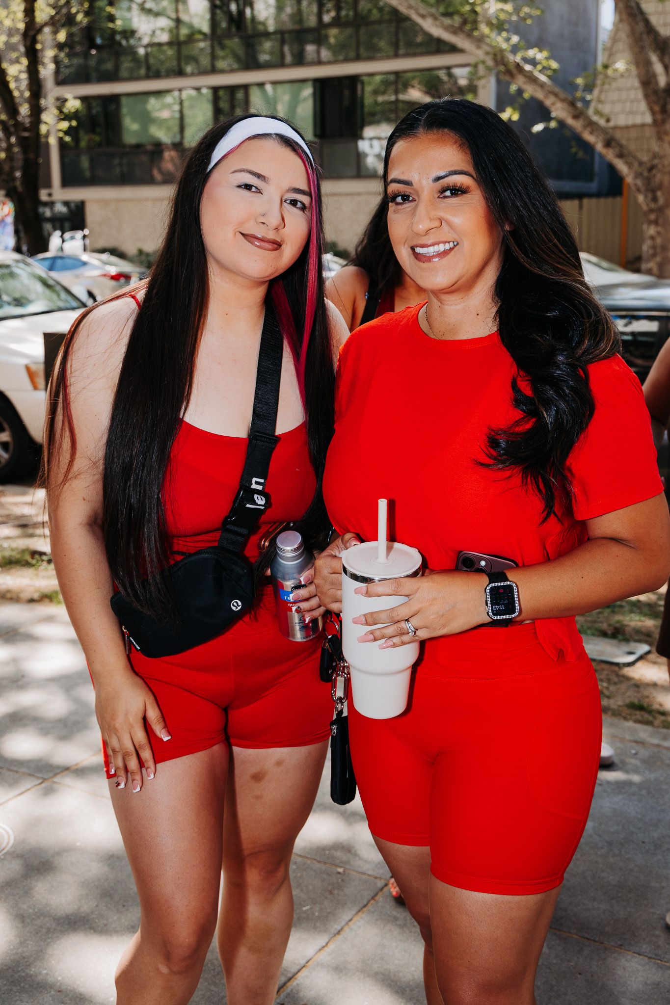 Two friends in red outfits pose together for a series of casual photos on a sunny day outdoors.