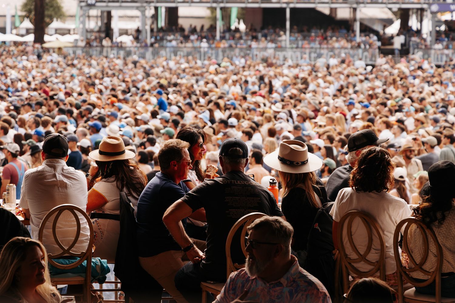 Large crowd of festival attendees gathered at an outdoor concert venue during daytime.