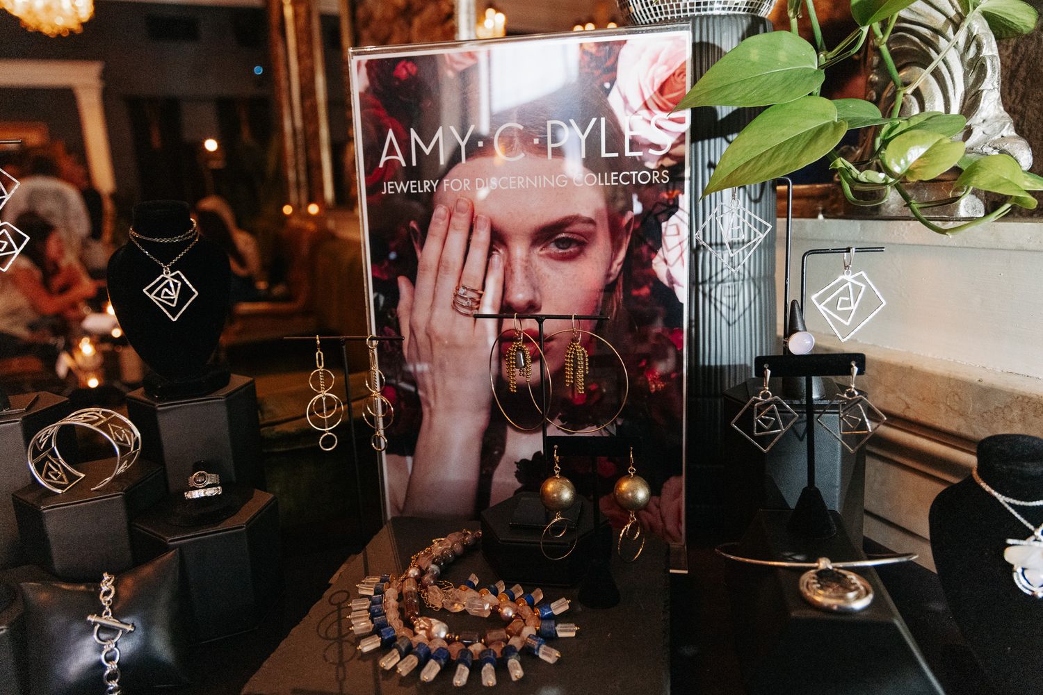 Amy CC Ryles jewelry collection display featuring necklaces, bracelets, and earrings on black stands.