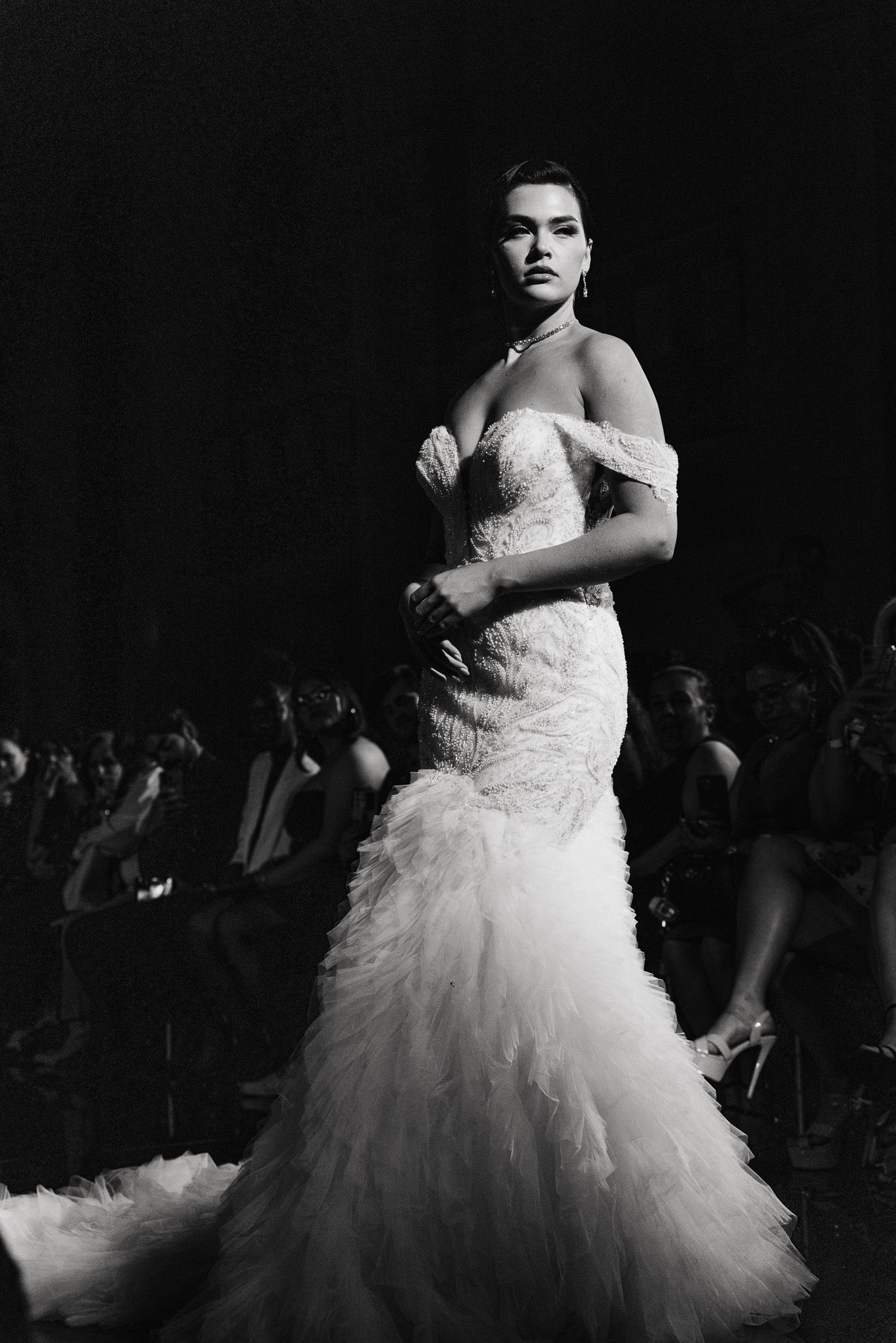 A dramatic black and white photo series showing a person in a flowing white wedding dress twirling and posing against a dark background.