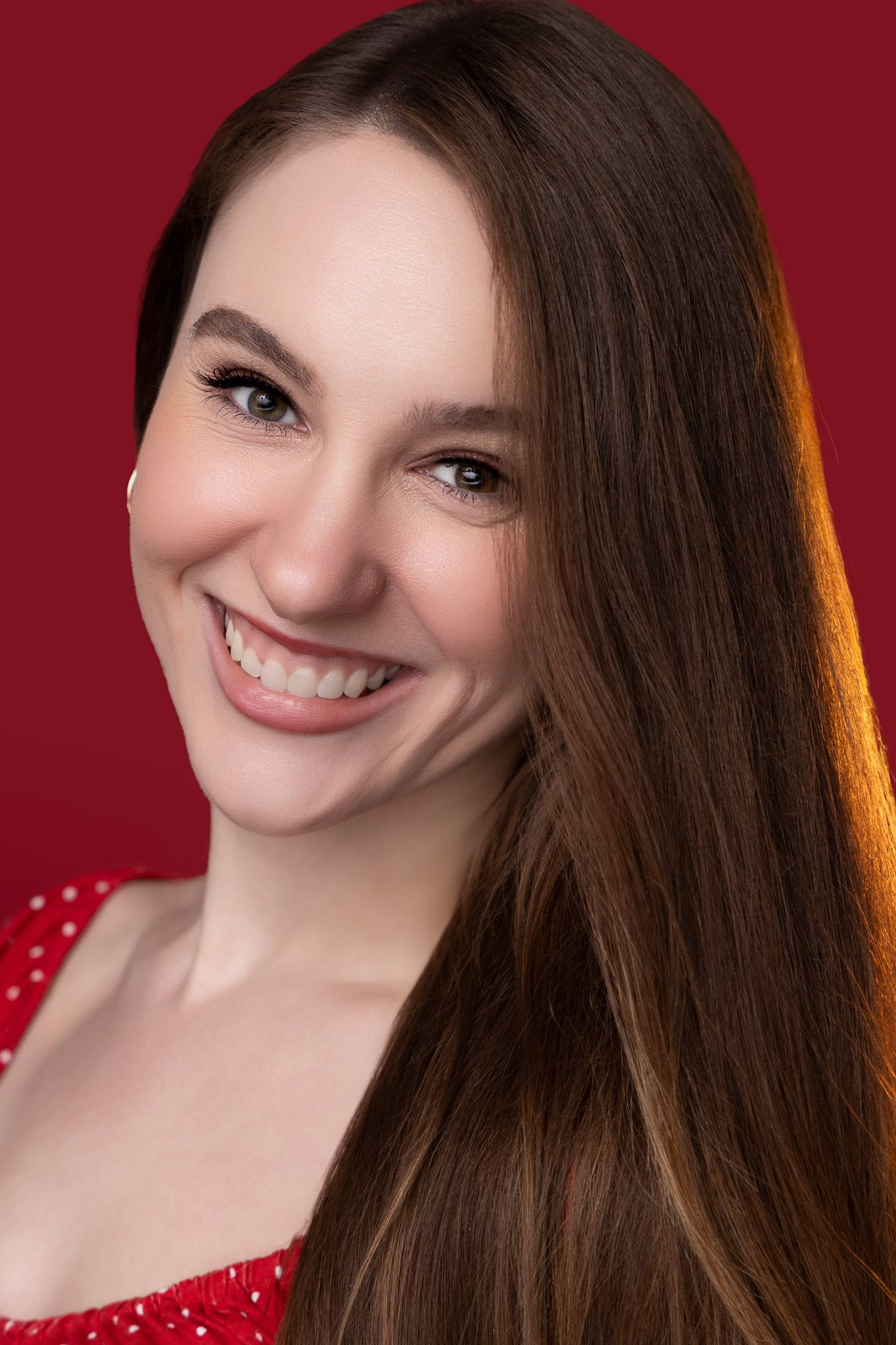 Portrait series with warm red background showing joyful expressions and long brown hair against dramatic lighting.