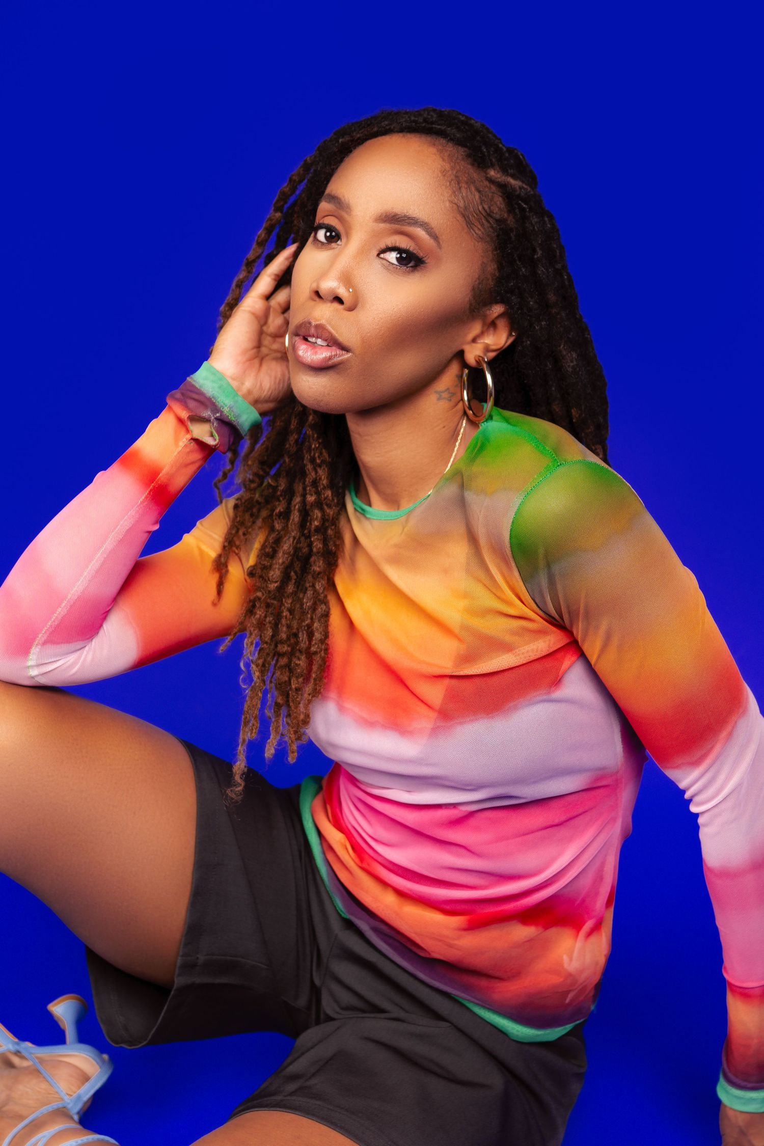 Colorful fashion photo series against blue background showing vibrant tie-dye top in energetic poses with dramatic lighting.