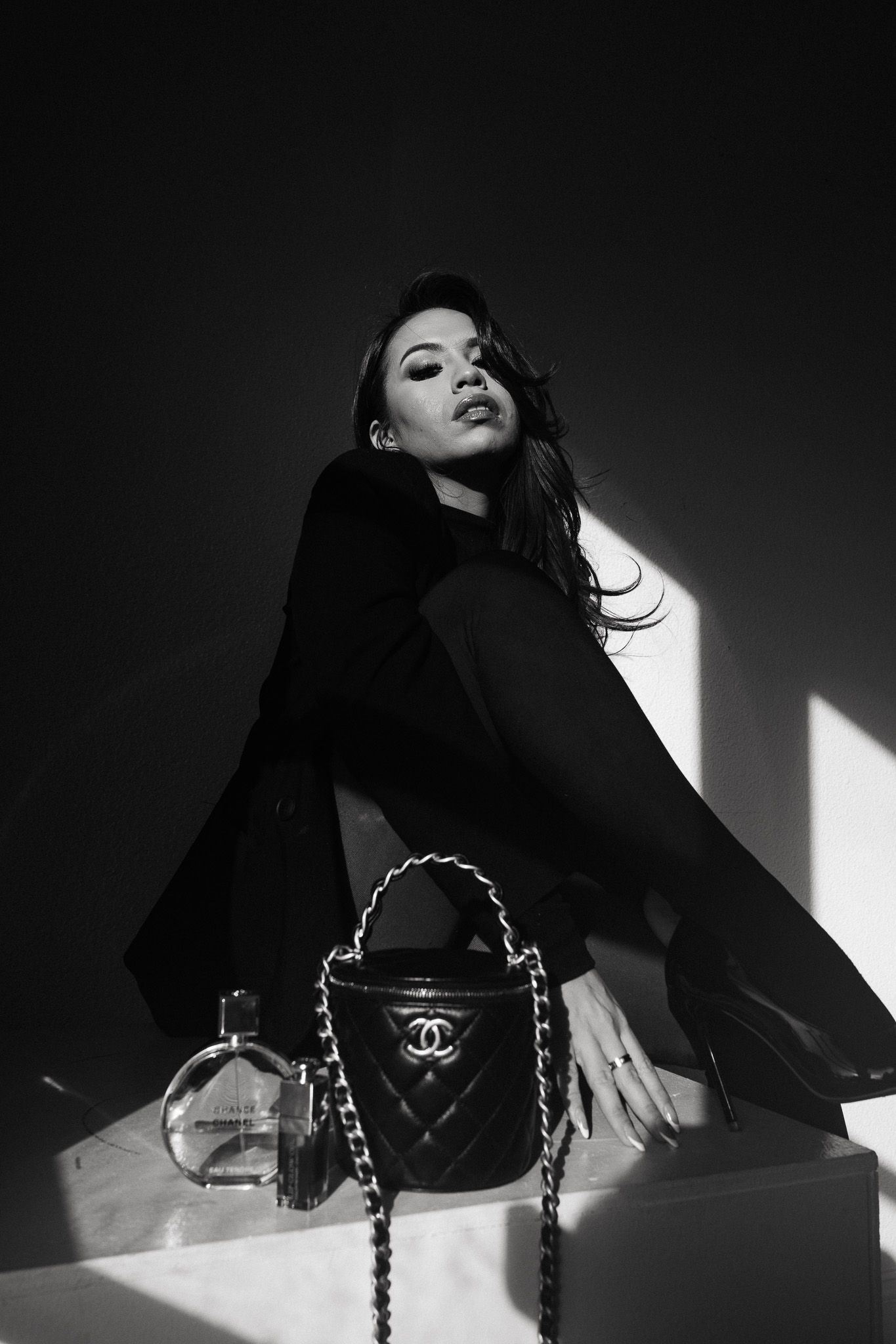 A black and white fashion photo sequence showing dramatic poses with a Chanel handbag in contrasting lighting.