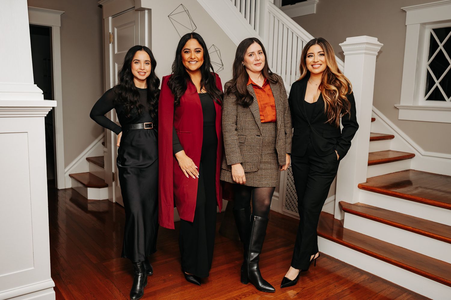 Friends gathered near an elegant white staircase in a modern home interior.