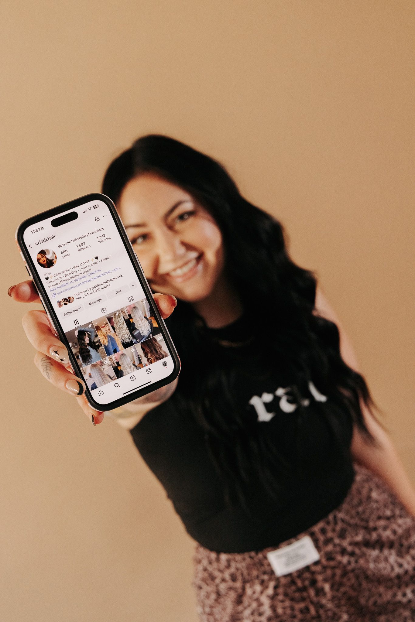 Person displaying phone screen while posing against neutral beige background.