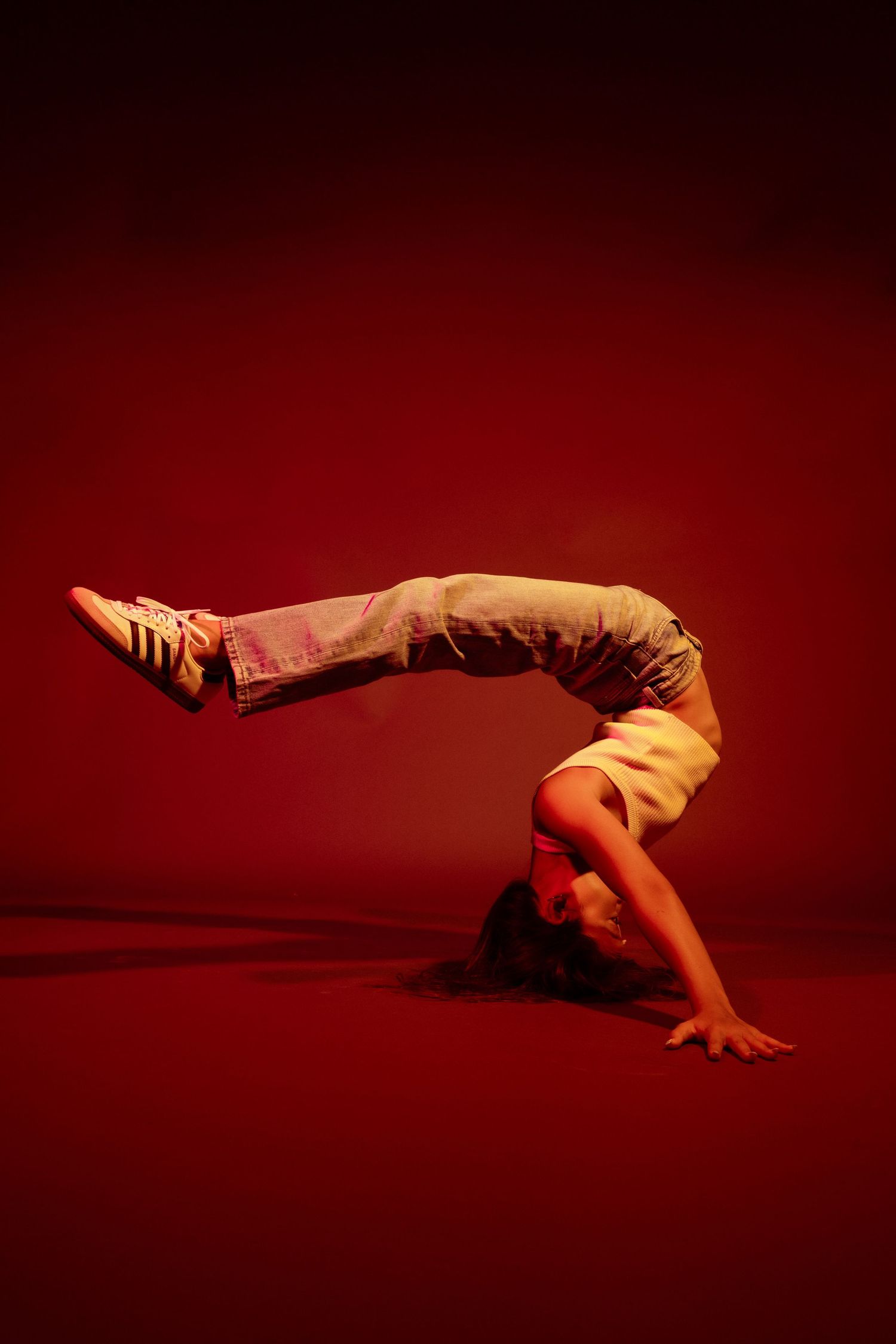 Dance sequence photographed against deep red background showing floor-based contemporary movements.