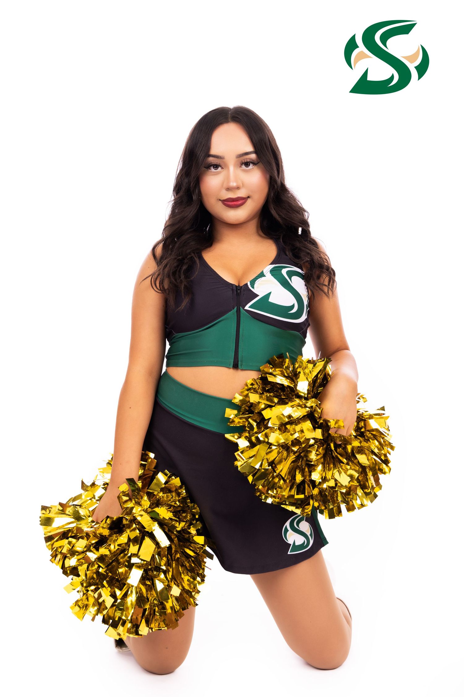 Athletic cheerleader in black and green uniform poses with gold pom poms against white background.