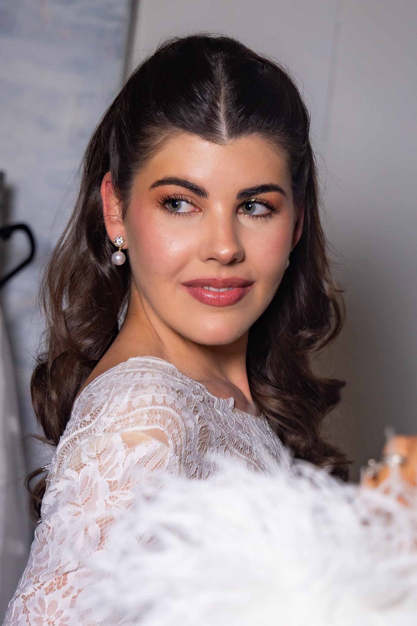 Elegant beauty shot featuring soft waves, natural makeup and white lace details against a light background.