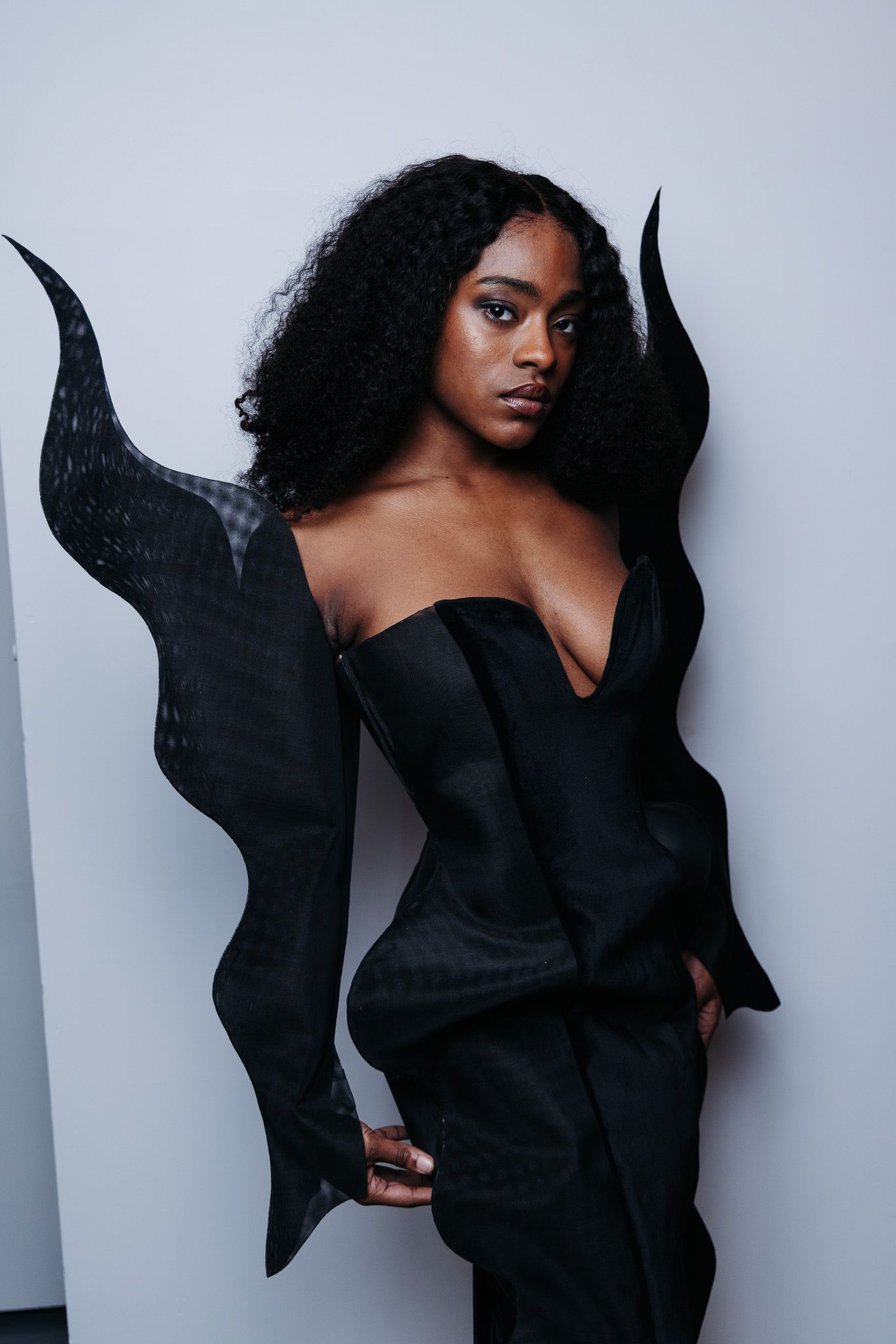 Artistic fashion portraits showing dramatic poses in a flowing black garment against a light background.