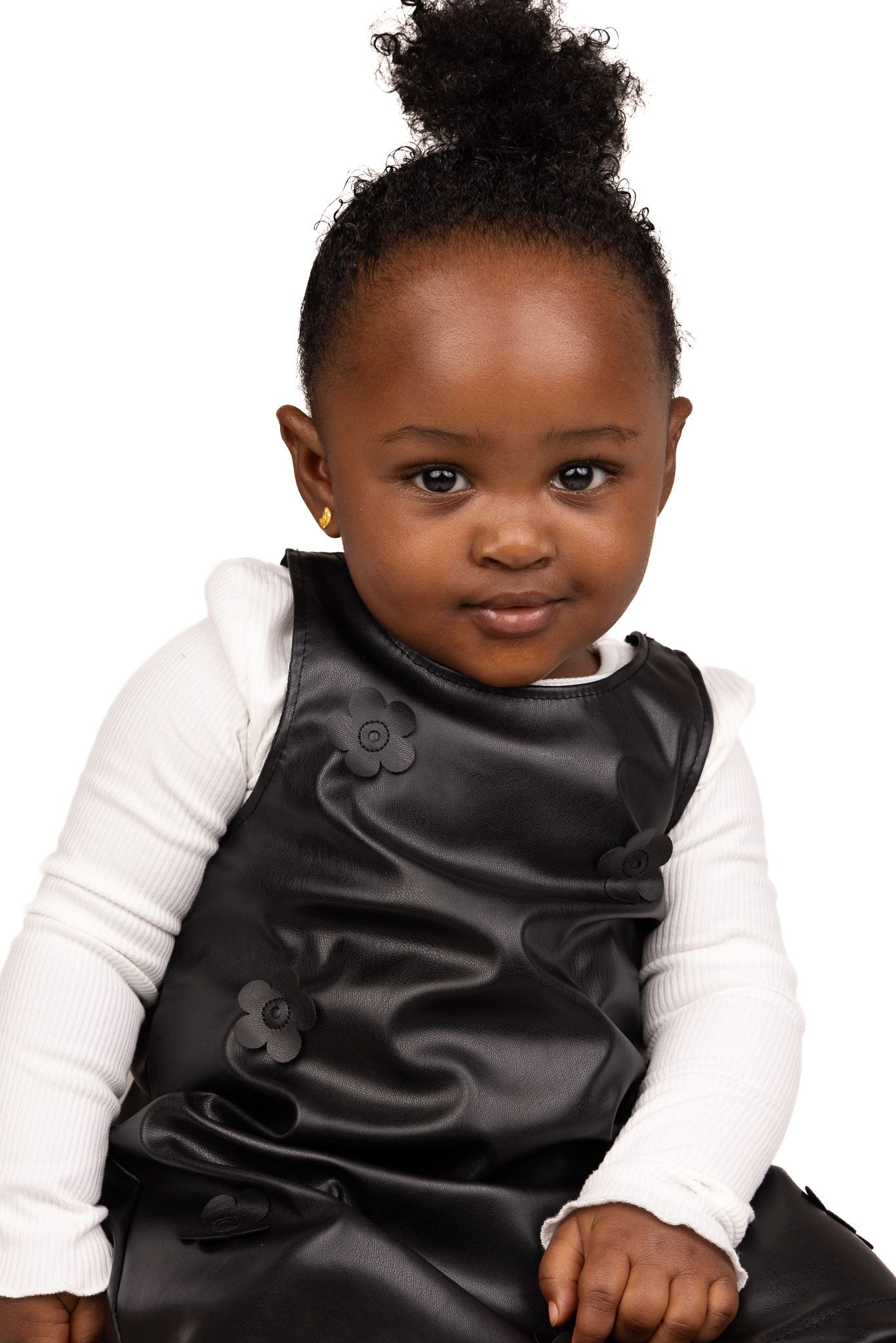 A smiling child wearing a black bib and white long sleeve shirt against a white background.