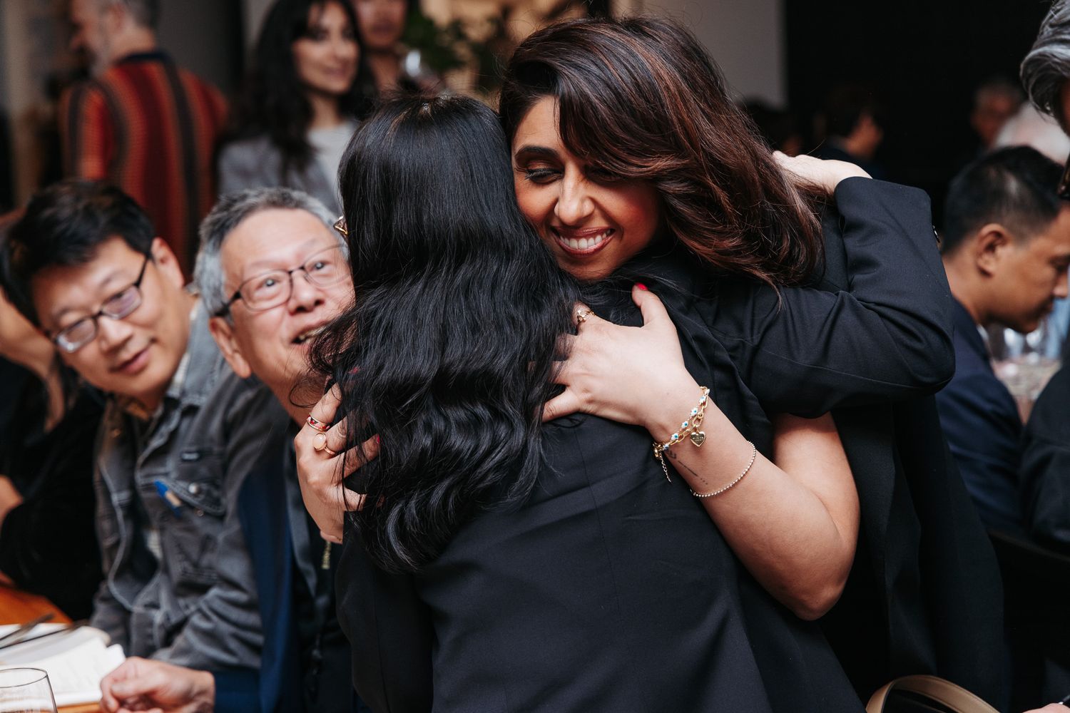 Celebratory moment at an indoor event with people embracing and laughing.