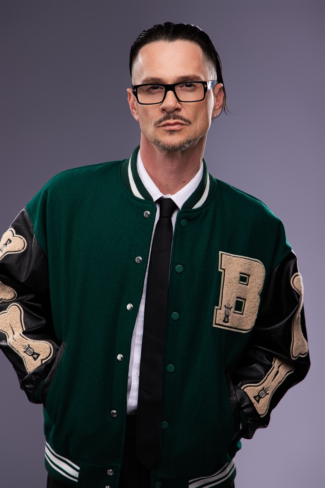 Person wearing a green varsity letterman jacket with leather sleeves and white trim poses in multiple shots.