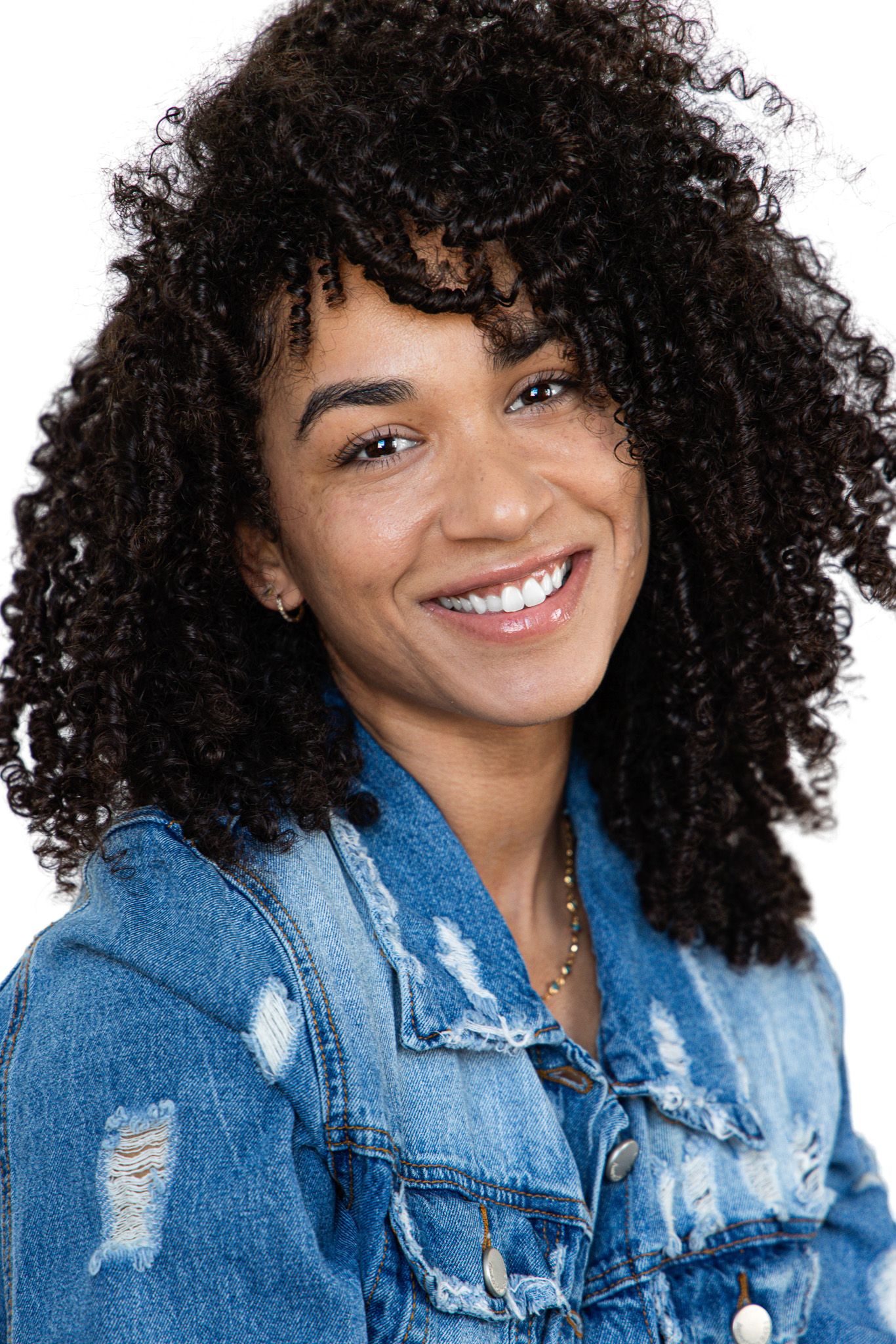 Collage of four photos showing someone with natural curly hair wearing a distressed denim jacket against a white background.