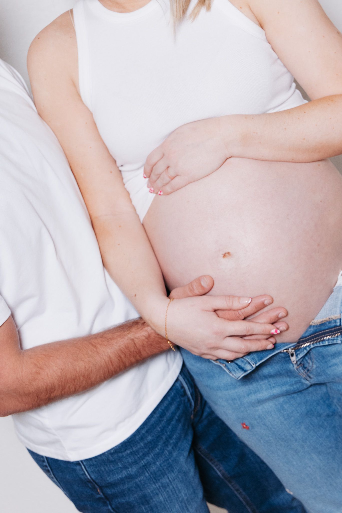 Close-up series showing hands pressing on stomach area through white shirt and blue jeans to demonstrate abdominal pain.