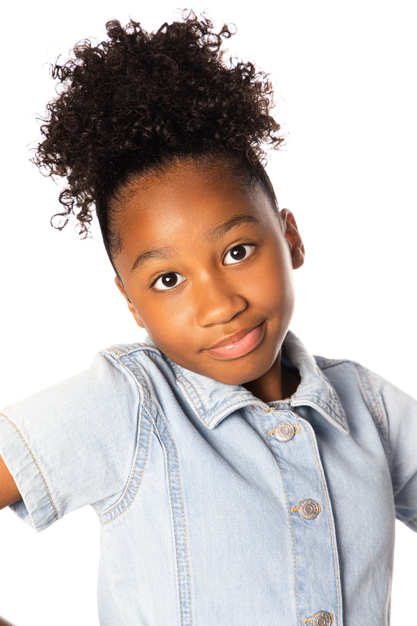 Studio portrait of a youth in denim jacket with natural curly hair styled up.