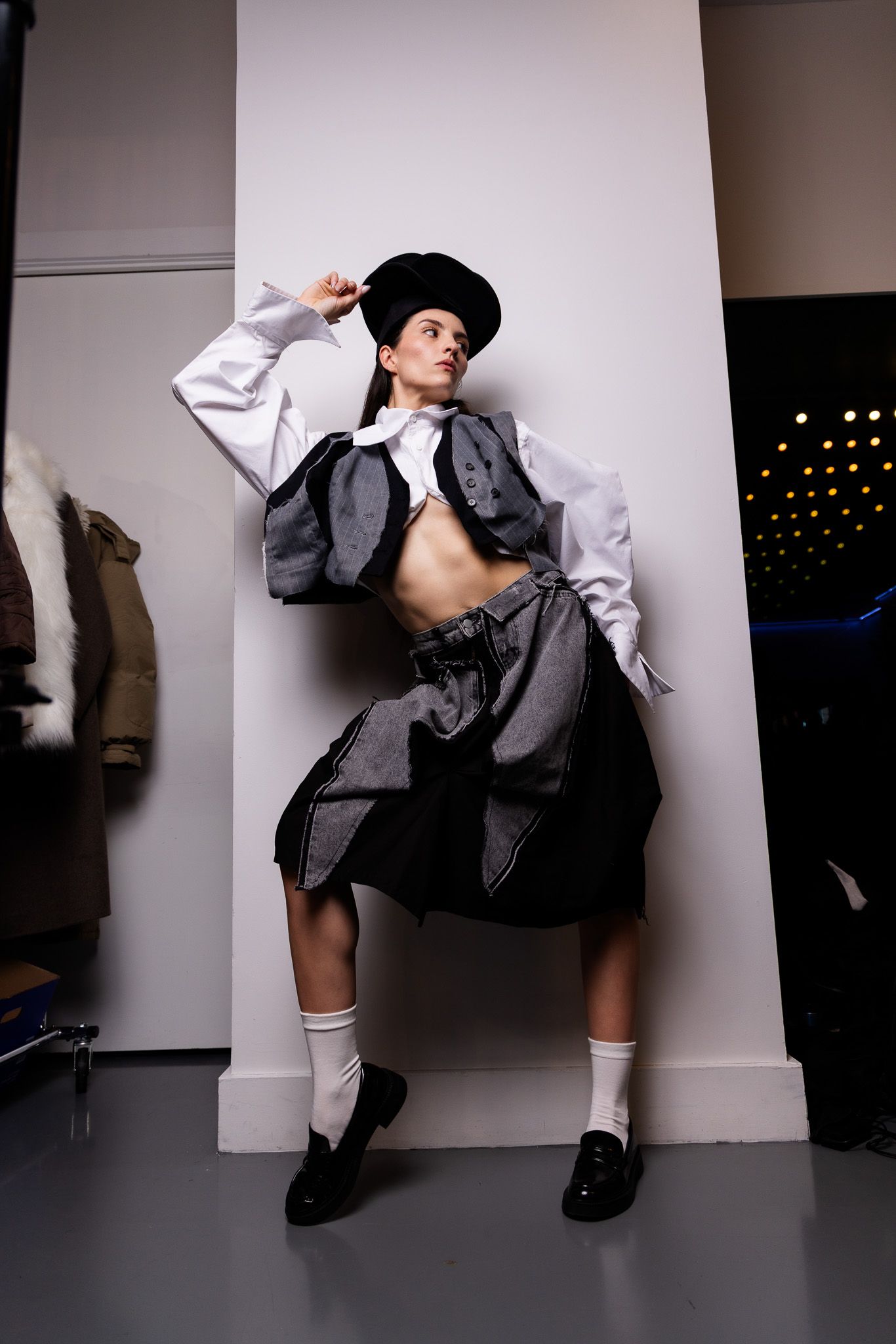 Series of dynamic fashion poses showing a model in a gray suit and white socks against a studio wall.