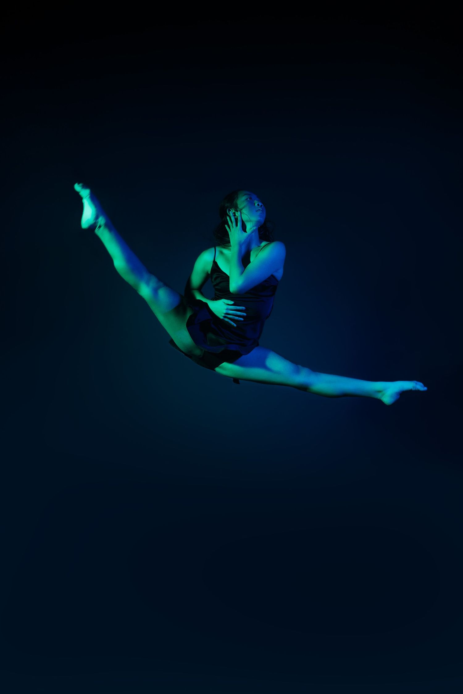 Ethereal dance performance captured in cool blue tones showing floating movements in darkness.
