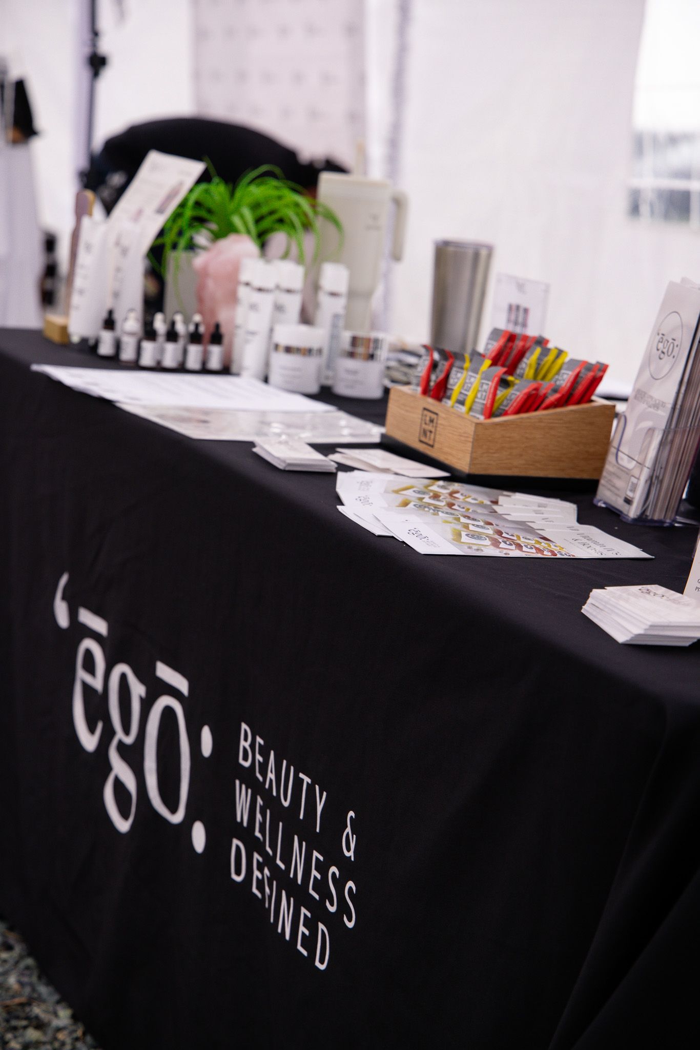 Product display table with black tablecloth showcasing various beauty and wellness items at a vendor event.