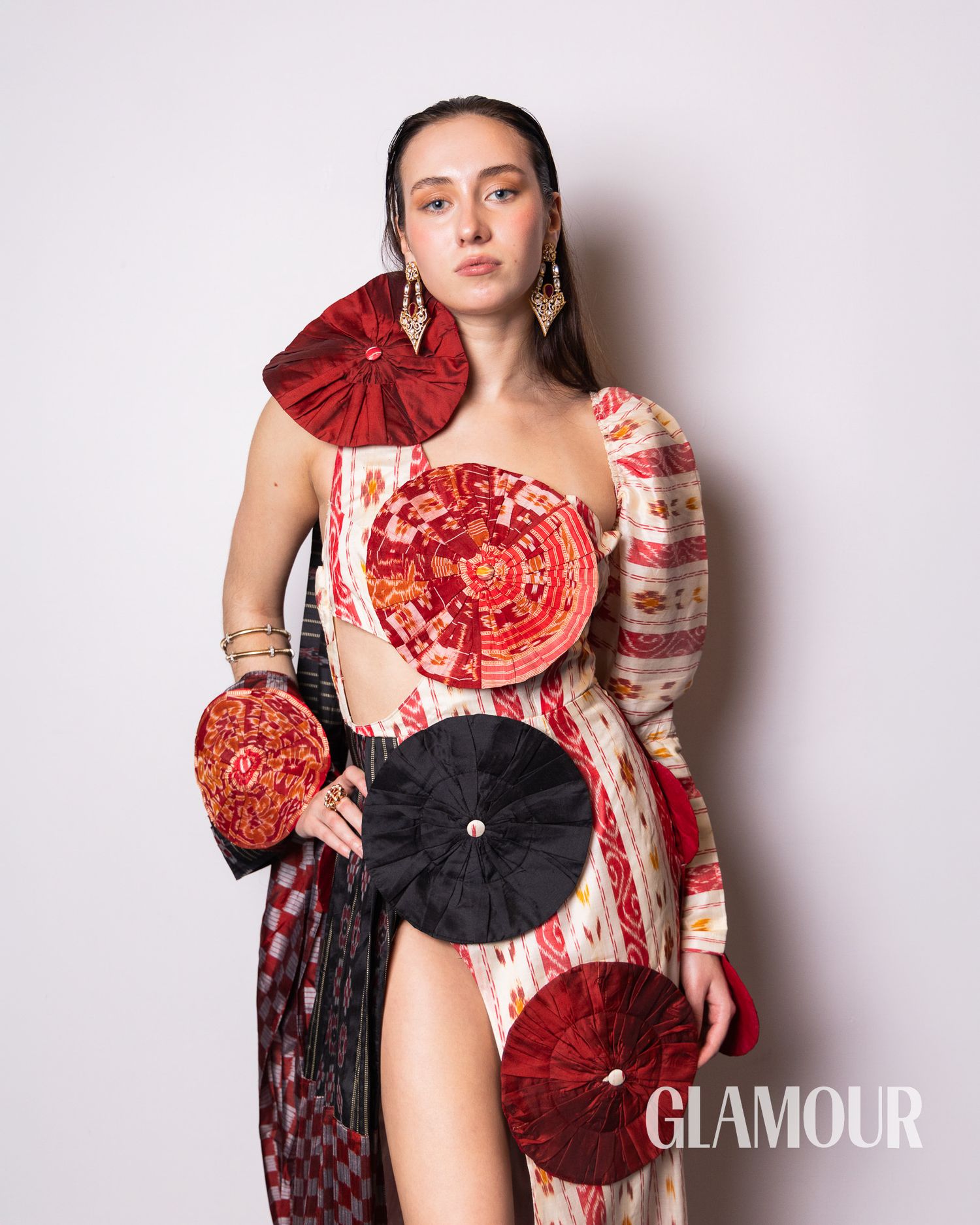 A dramatic red and white dress adorned with circular fabric embellishments in a Glamour magazine photoshoot.