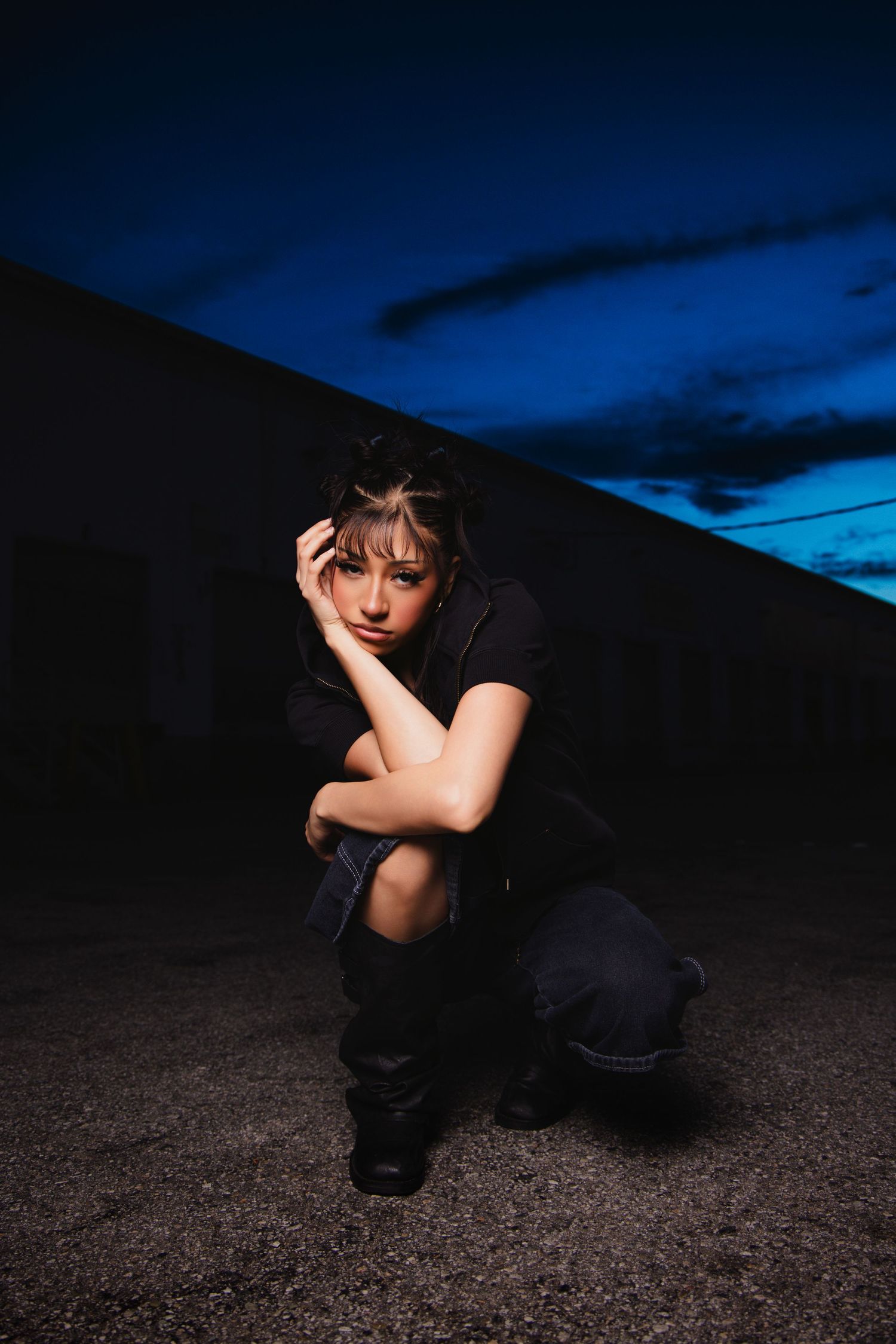 Artistic portrait series of a figure in dark clothing against a moody blue twilight sky and rocky terrain.
