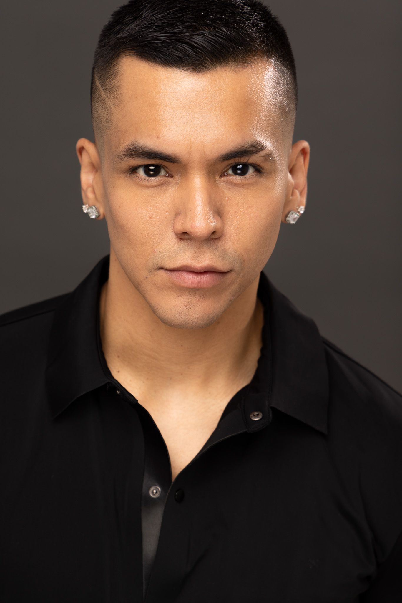 Professional headshot of a person in a black collared shirt against a dark backdrop.