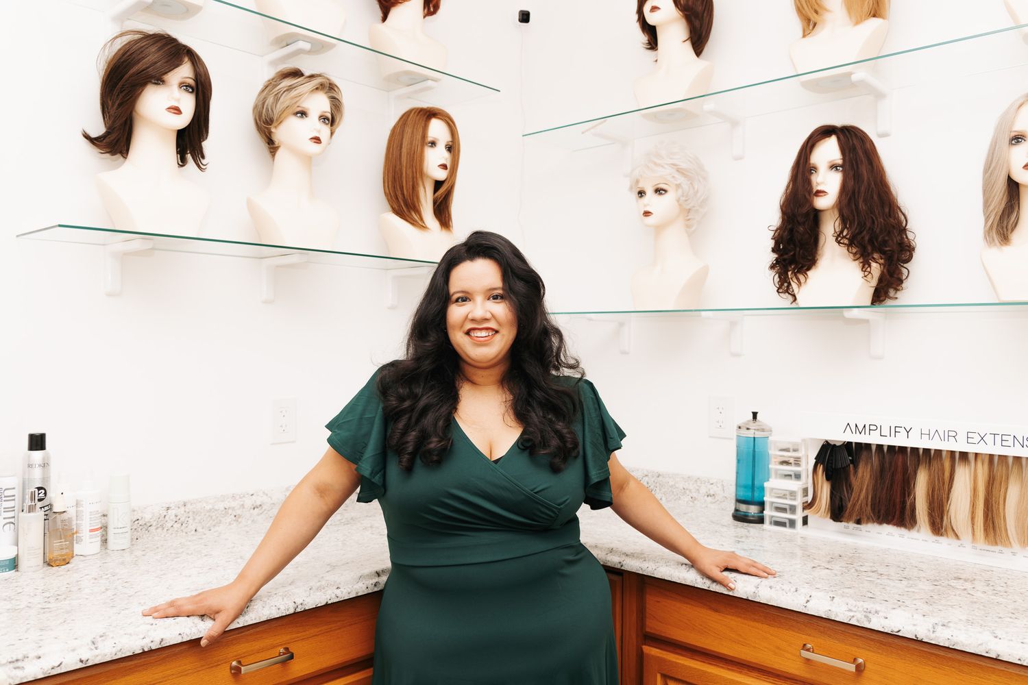 Interior of a wig shop with various hairstyles displayed on mannequin heads along white walls.
