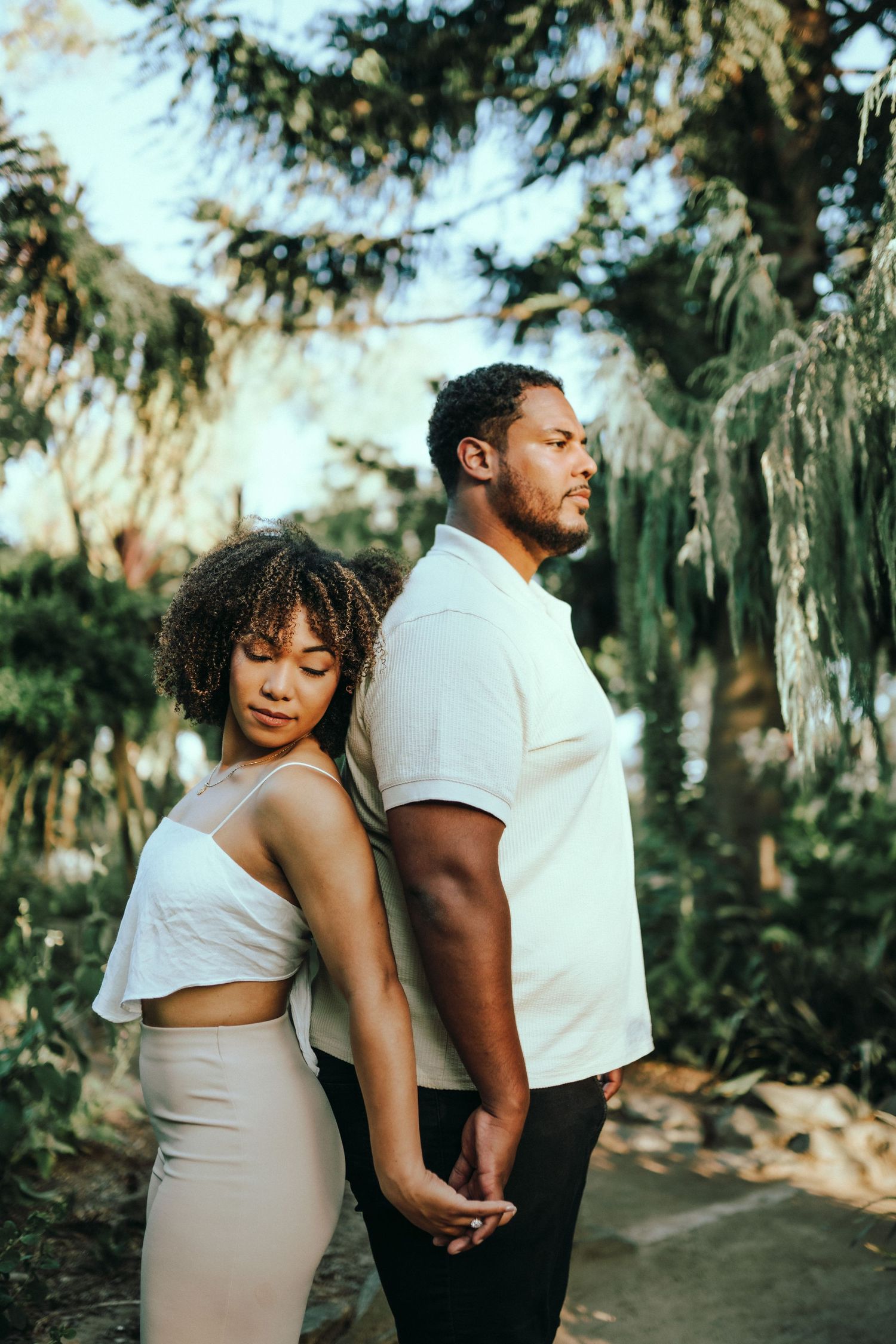 Romantic couple embraces in a lush garden setting with Spanish moss draped trees creating a dreamy atmosphere.