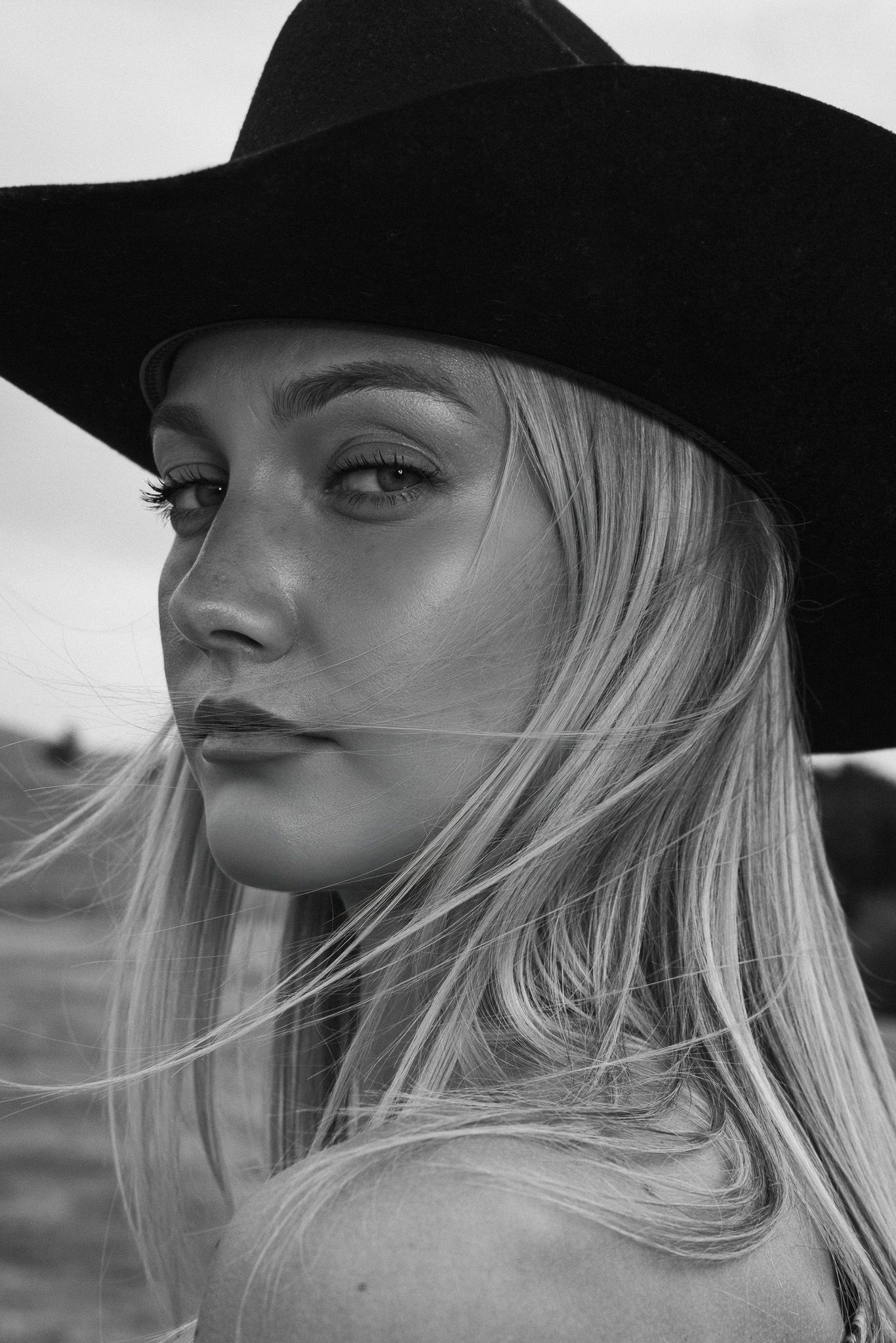 A series of black and white profile portraits showing a blonde woman in a dark hat gazing into the distance.
