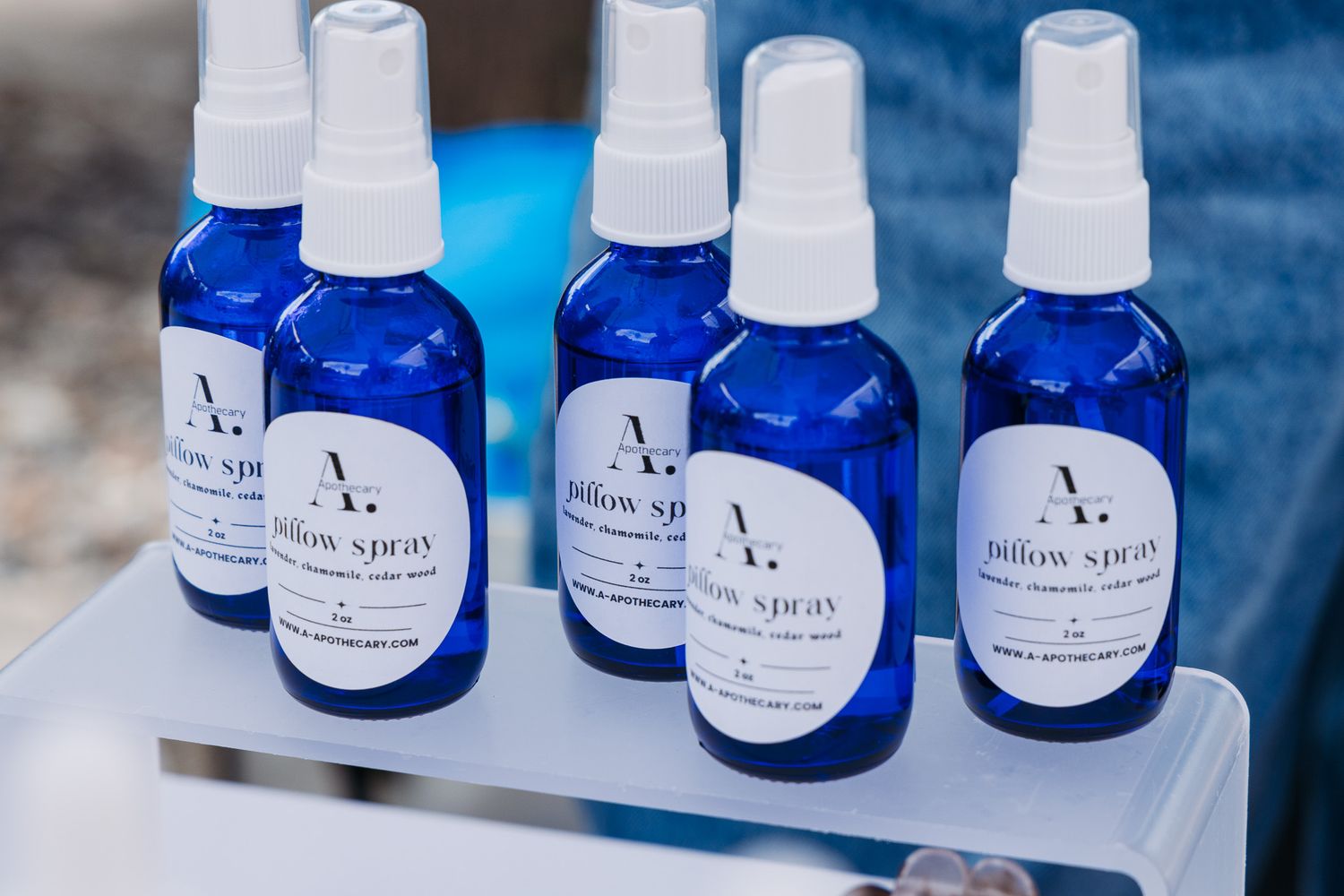 Blue glass pillow spray bottles with white labels displayed on tray.