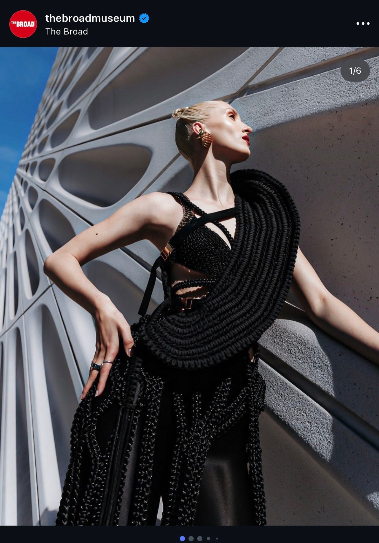 Model in black avant-garde woven gown poses outside The Broad Museum's iconic honeycomb facade in Los Angeles.