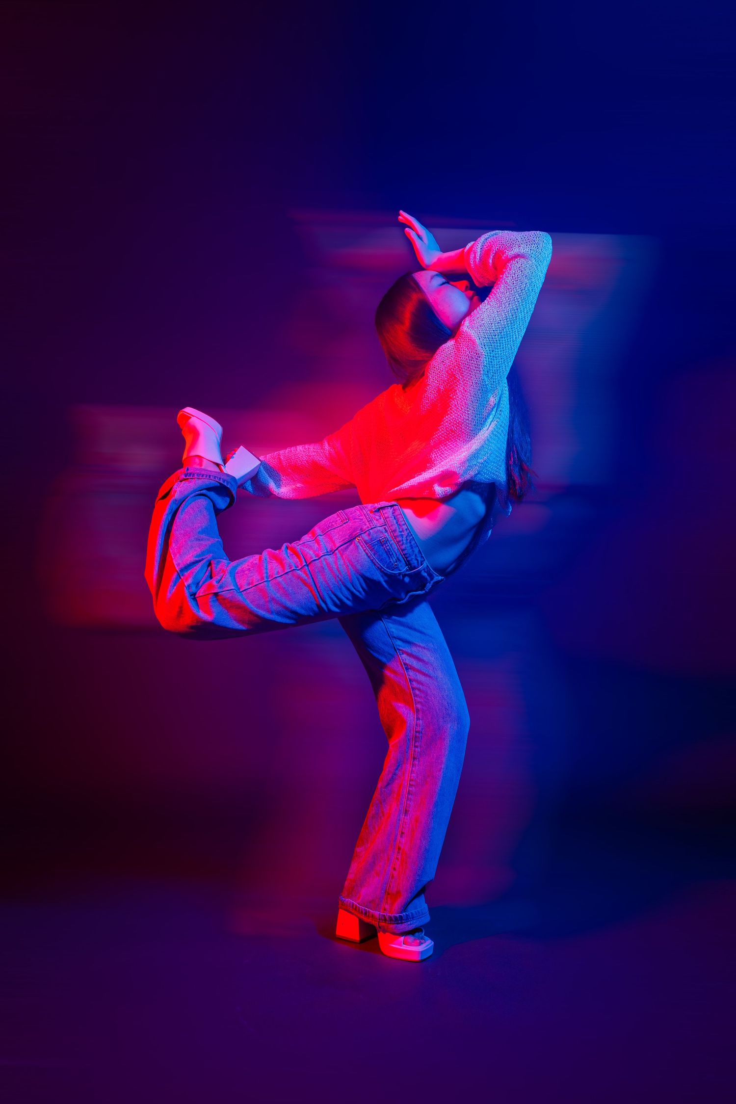 Modern dancer performing expressive movement in striking red and blue lighting.