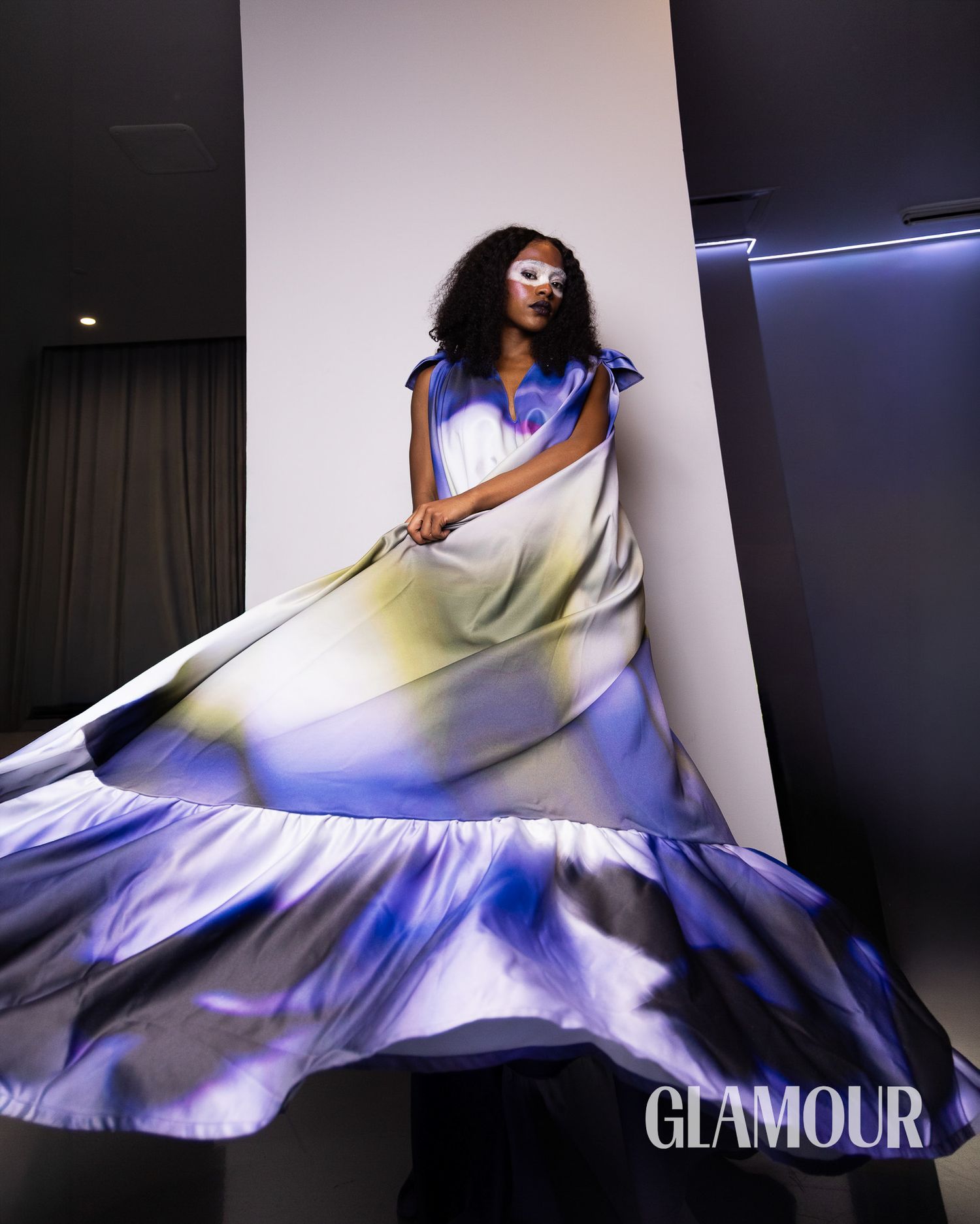 A flowing blue and white gown swirls dramatically in a fashion photoshoot for Glamour magazine.