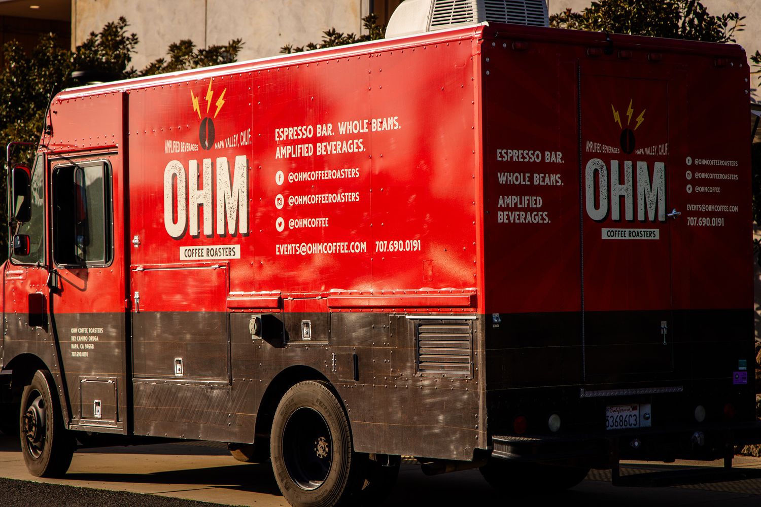 A line of red OHM delivery trucks parked in a row showing company branding.