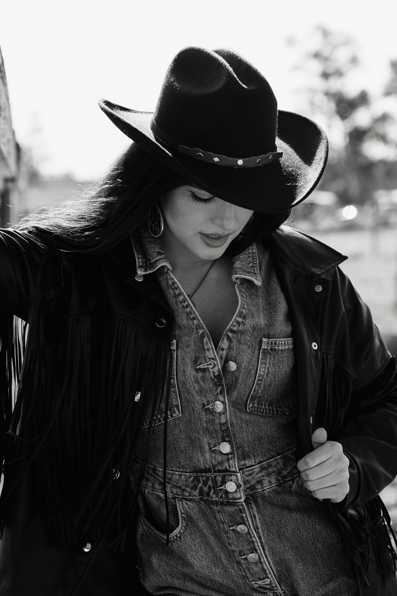 Black and white portrait of a western style outfit with denim jacket and black cowboy hat.