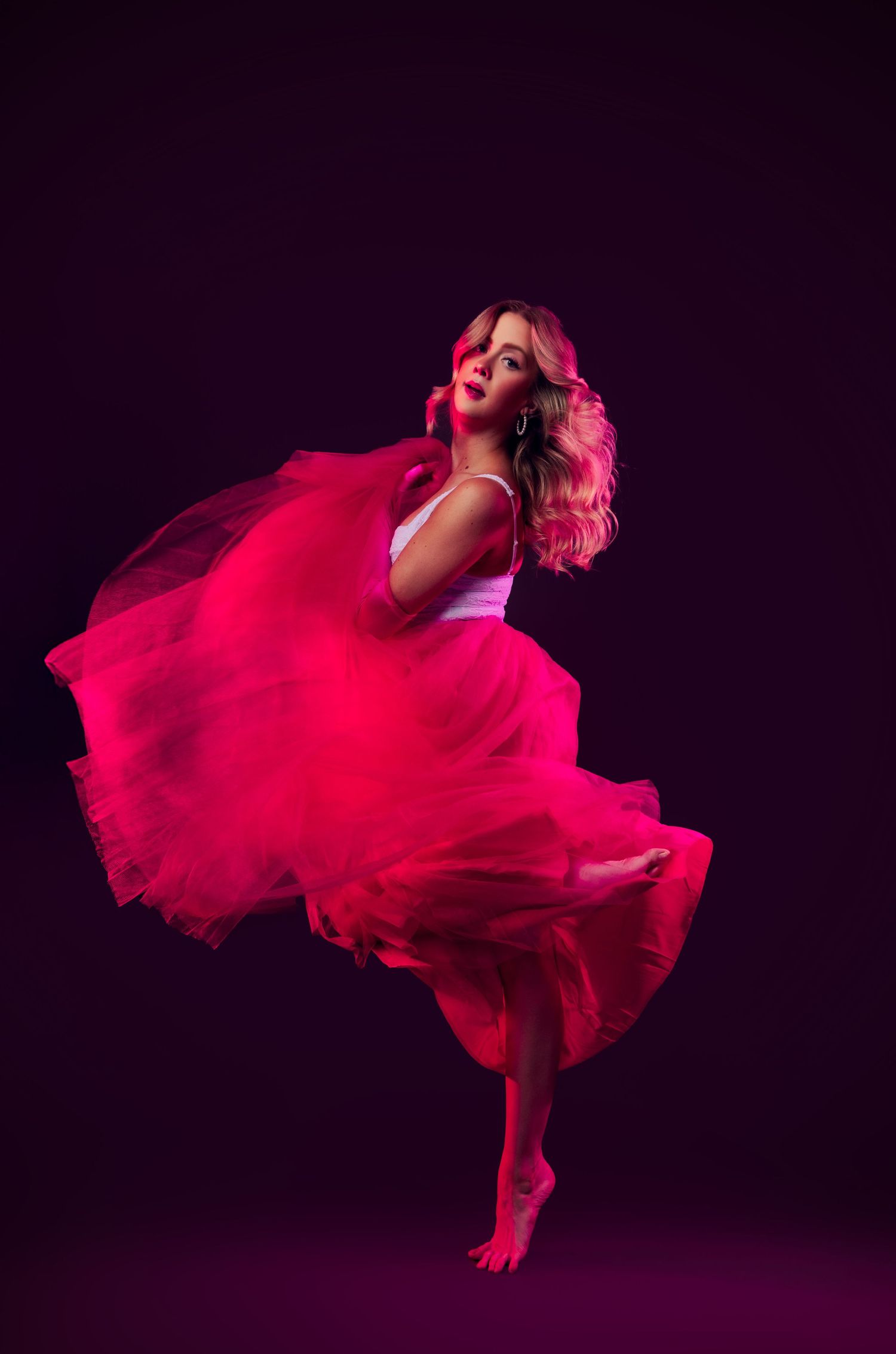 A dancer in a flowing red dress twirls gracefully against a dark background creating a stunning motion effect.