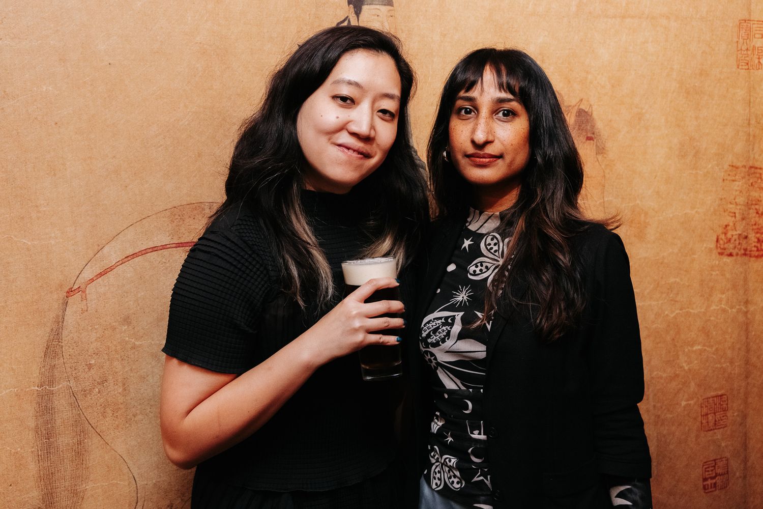 Group photo of attendees at a social gathering against a warm-toned wall.