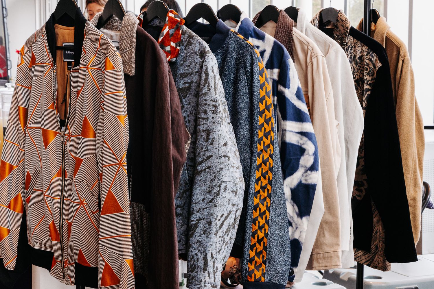 Row of stylish jackets with geometric patterns and prints hanging on a clothing rack.