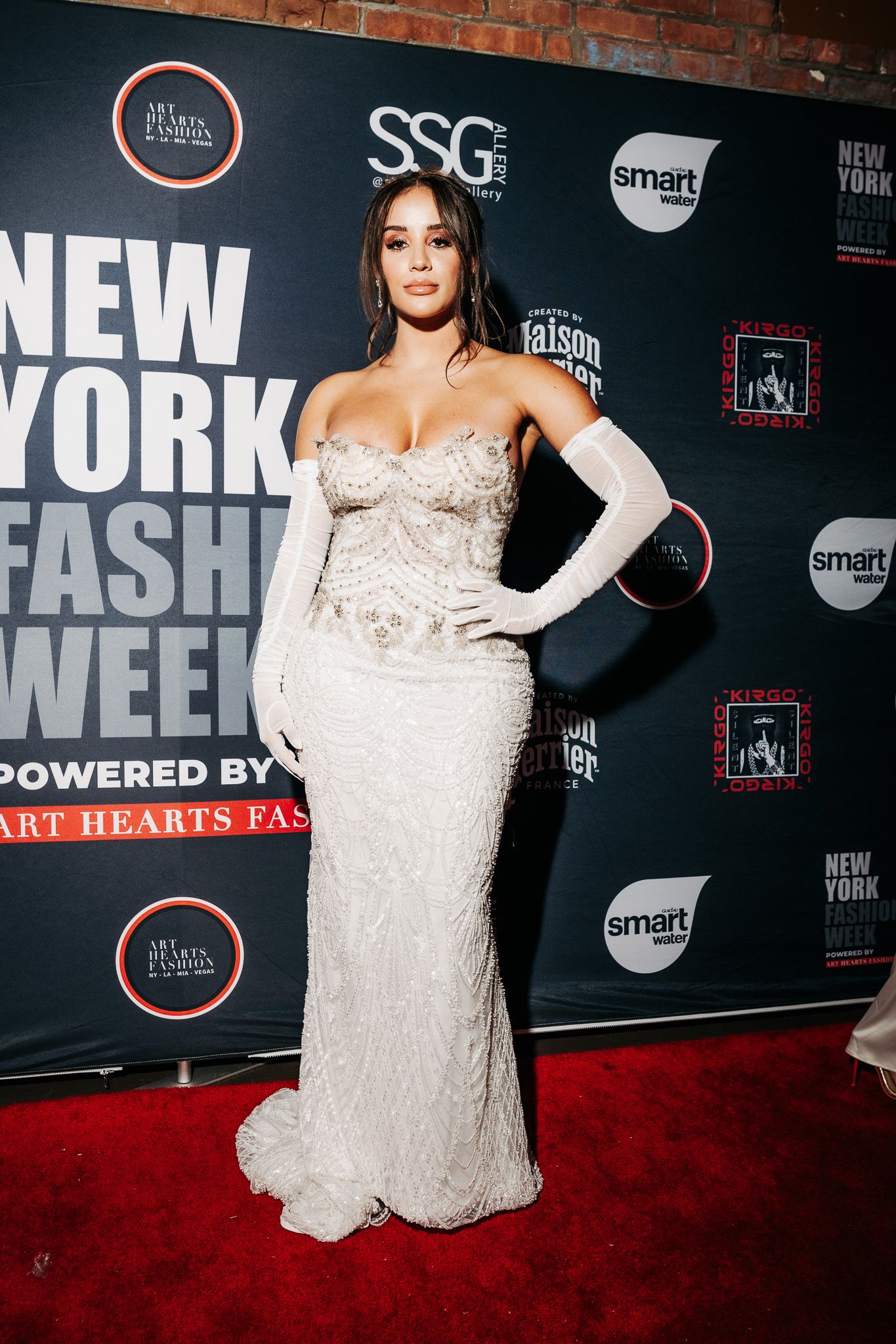 A model poses in a white lace strapless gown on the red carpet at New York Fashion Week.
