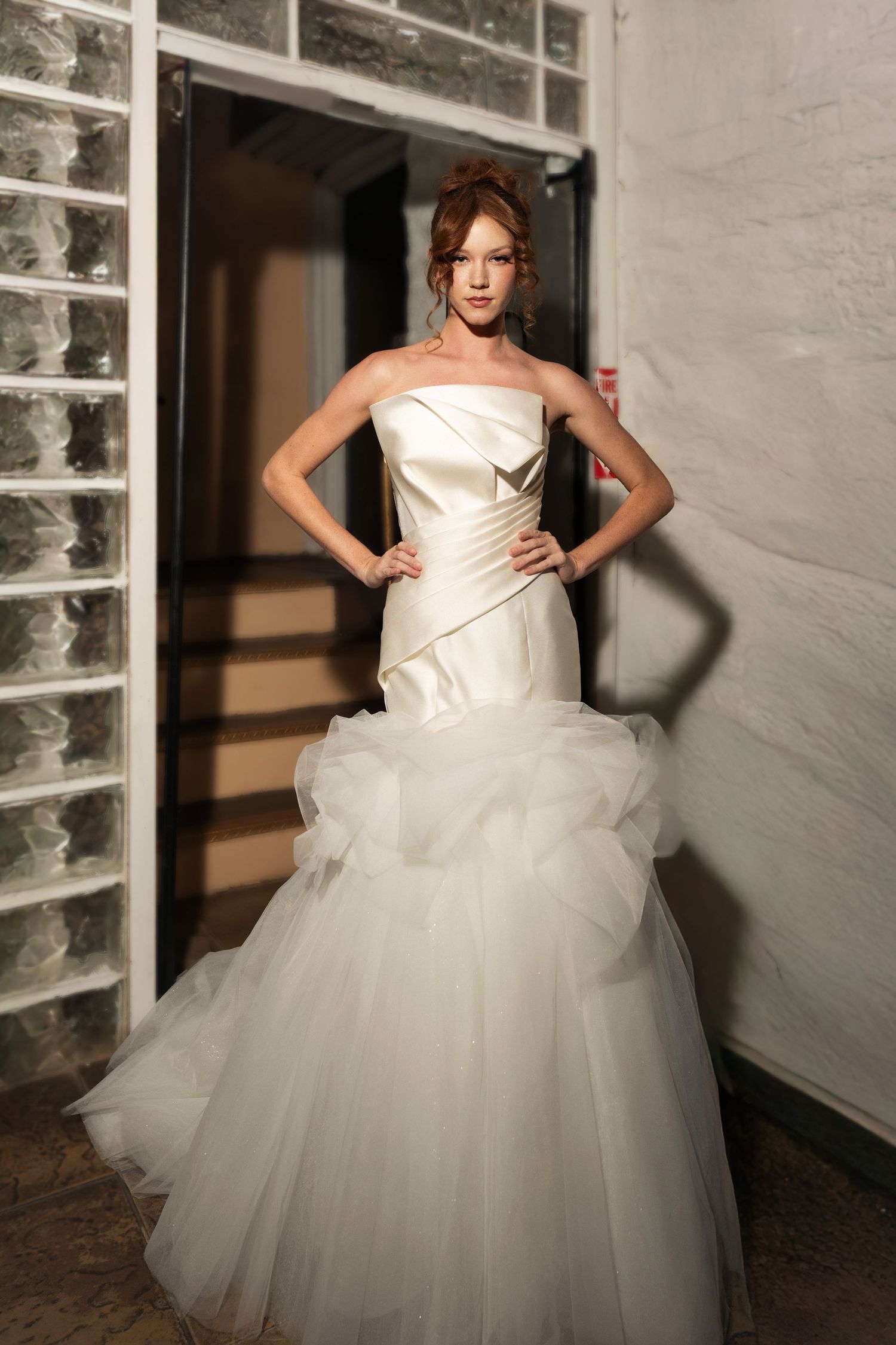 Dramatic bridal gown photoshoot with structured bodice and full tulle skirt against glass block windows.