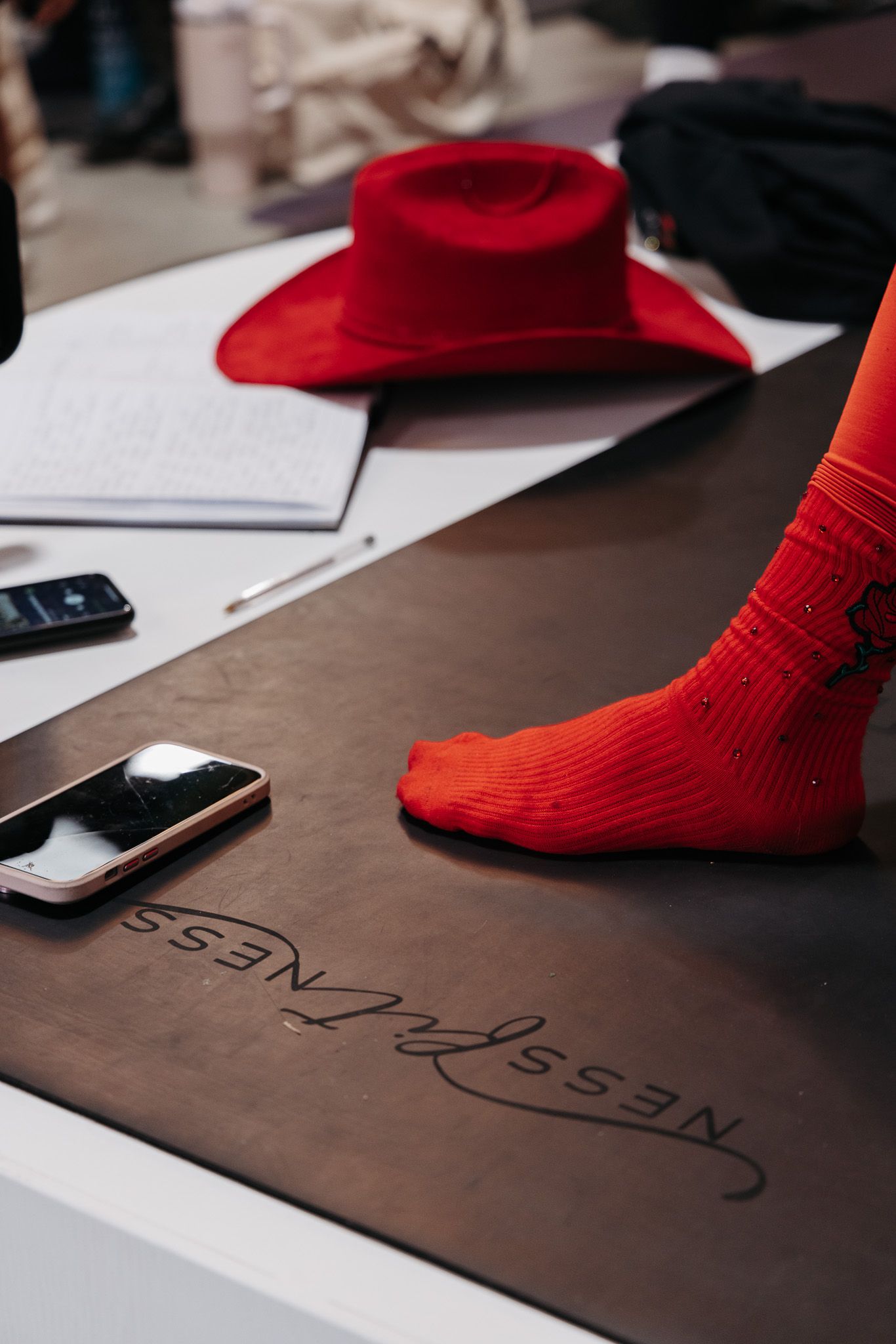 Red socks on a dark surface next to papers and mobile devices in a minimalist setting.