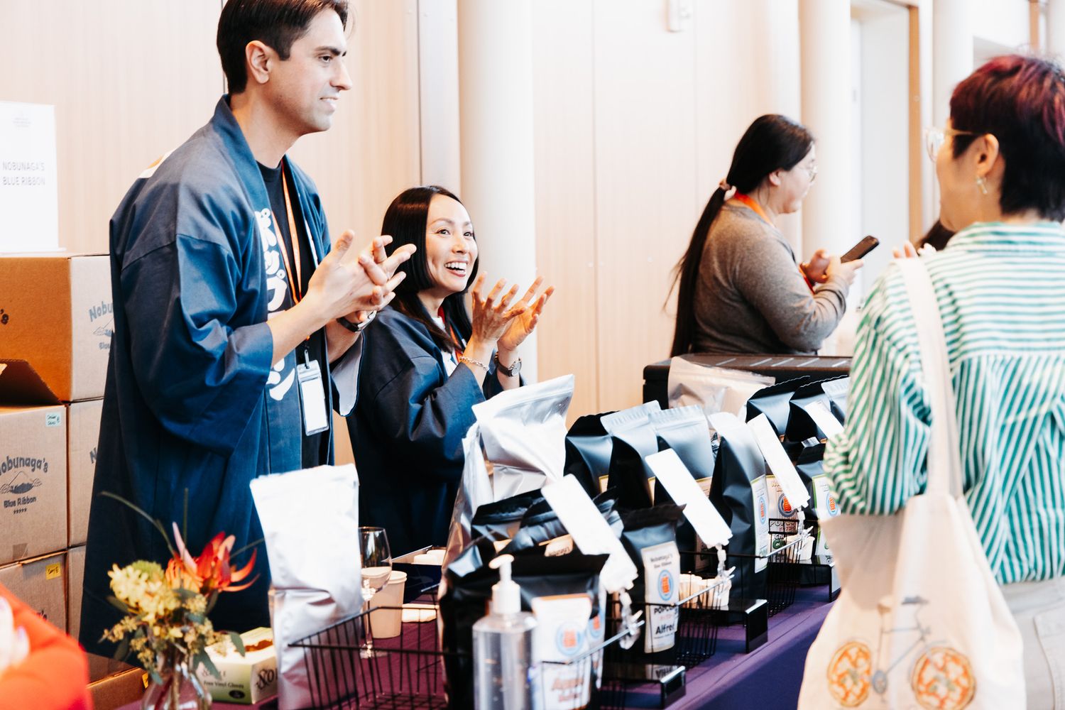 Vendors showcase coffee and beverages at a bustling market stall with equipment displays.